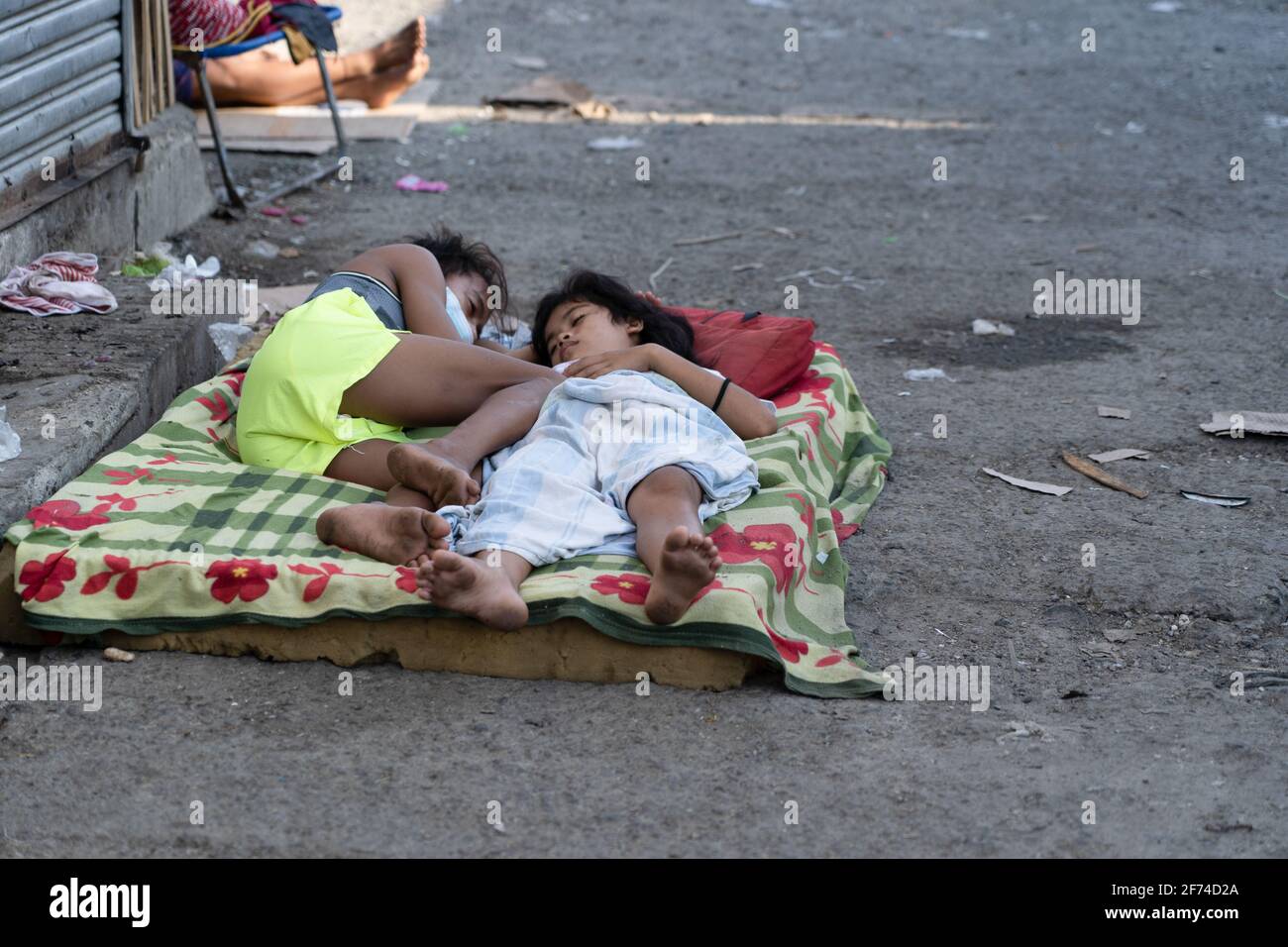 I bambini dormono su un materasso sottile nella strada all'interno di una zona povera di Cebu City, Filippine Foto Stock