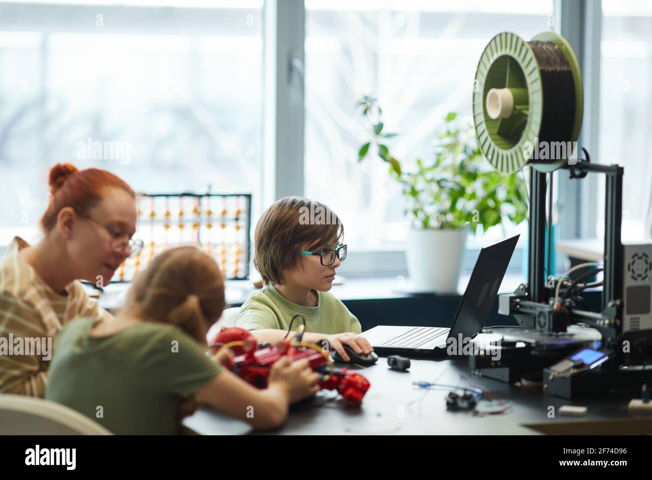 Vista laterale ritratto di bambini parti di stampa 3D per robot durante la classe di ingegneria a scuola moderna, copia spazio Foto Stock