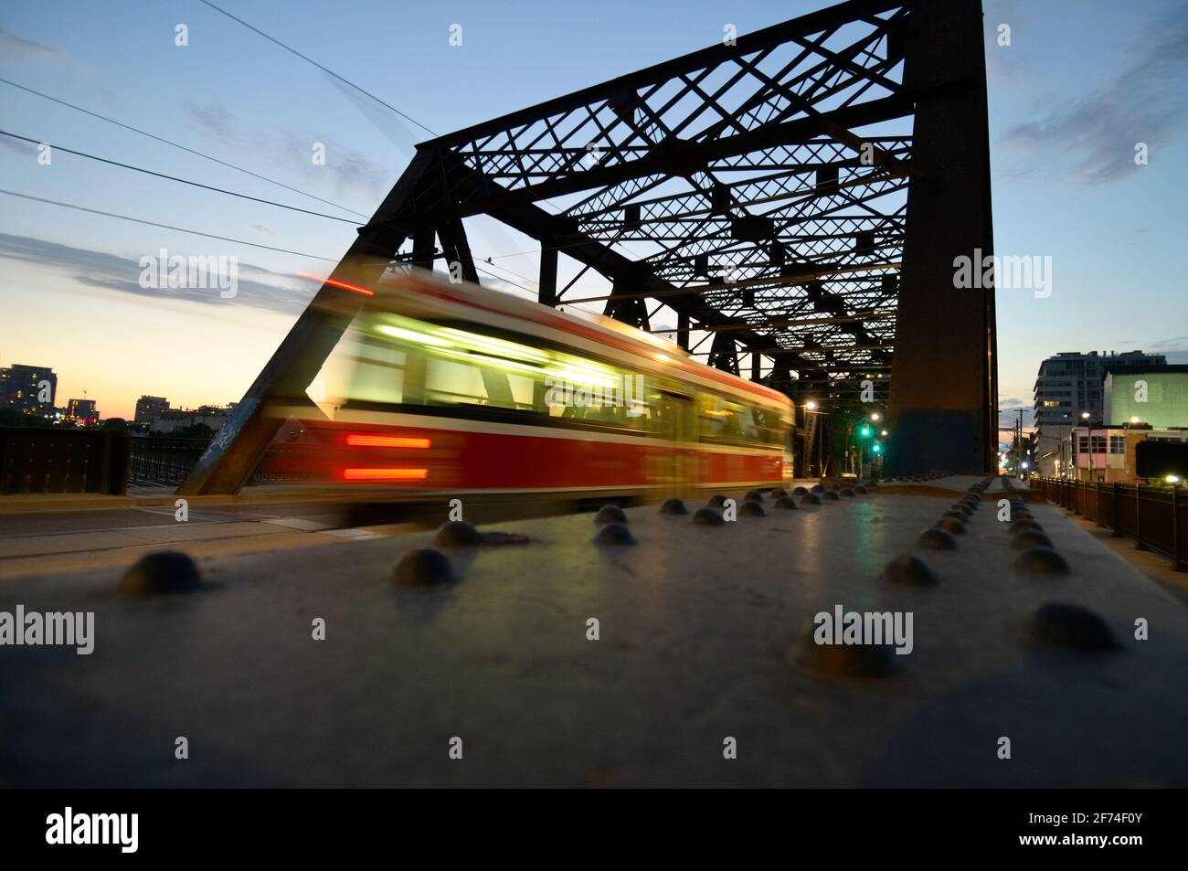 un tram (tram) passa attraverso un ponte di capriate al crepuscolo - sfocatura del movimento Foto Stock