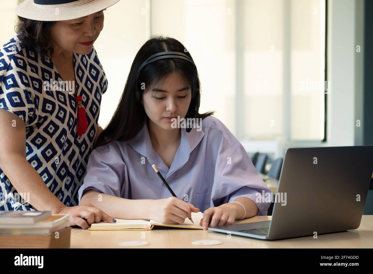 Madre asiatica con il notebook che insegna figlia per imparare o studiare in linea a casa, Homeschooling concetto in linea. Foto Stock