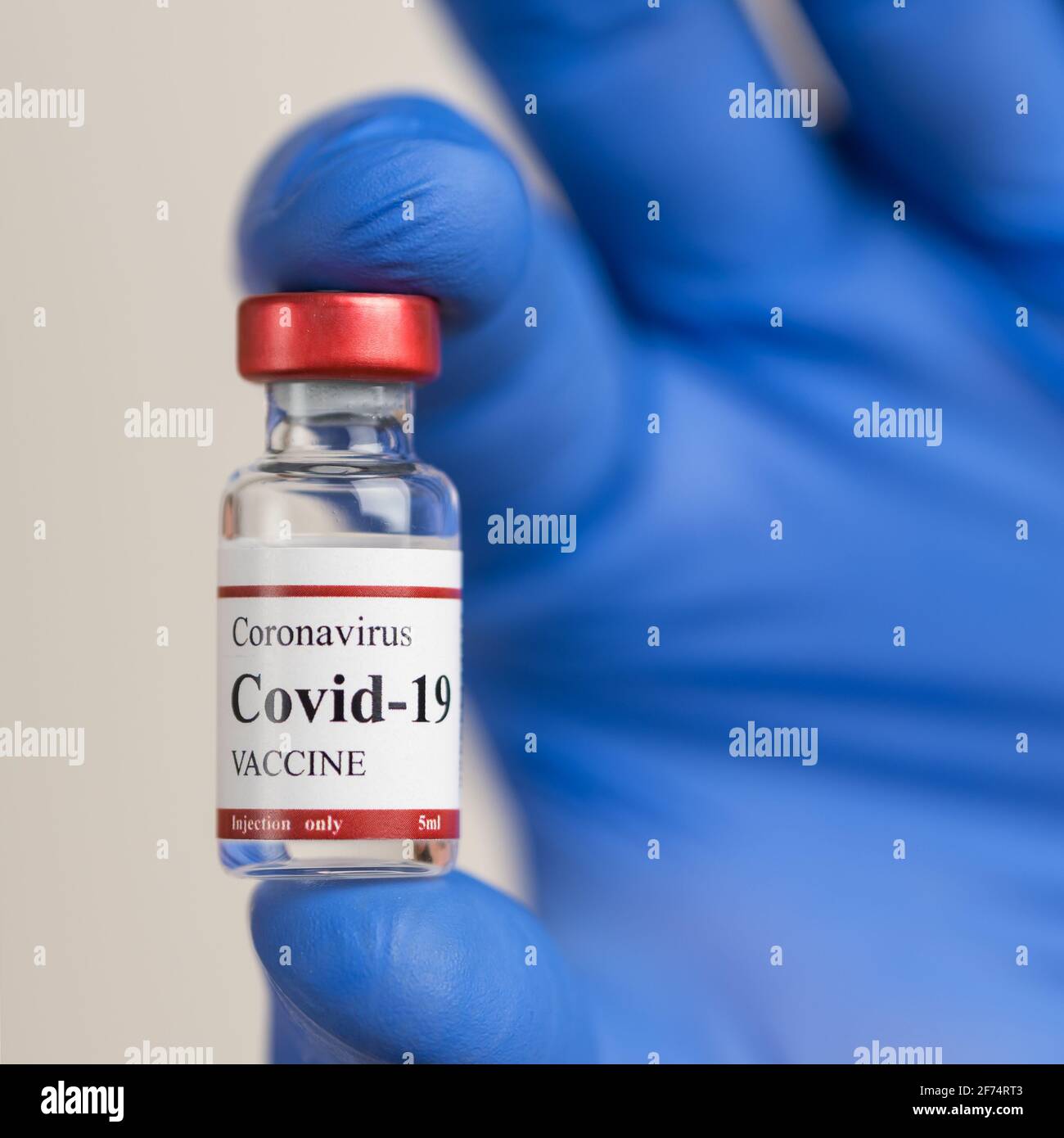 I guanti blu in lattice per i medici contengono il flaconcino di vaccino per coronavirus Covid-19. Foto Stock