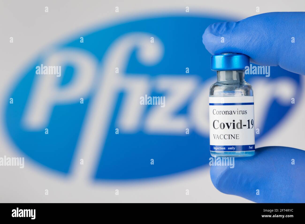 La mano del medico in guanti di lattice blu contiene il flaconcino di vaccino del coronavirus Covid-19. Foto Stock