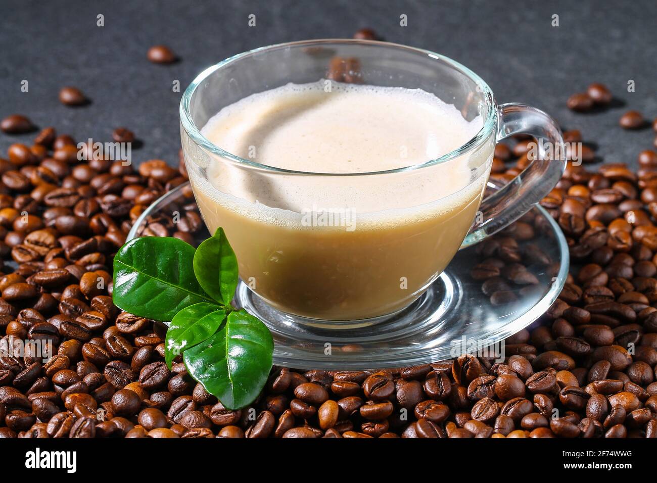 Tazza di caffè su un tavolo grigio con chicchi di caffè e foglie di caffè. Primo piano. Foto Stock