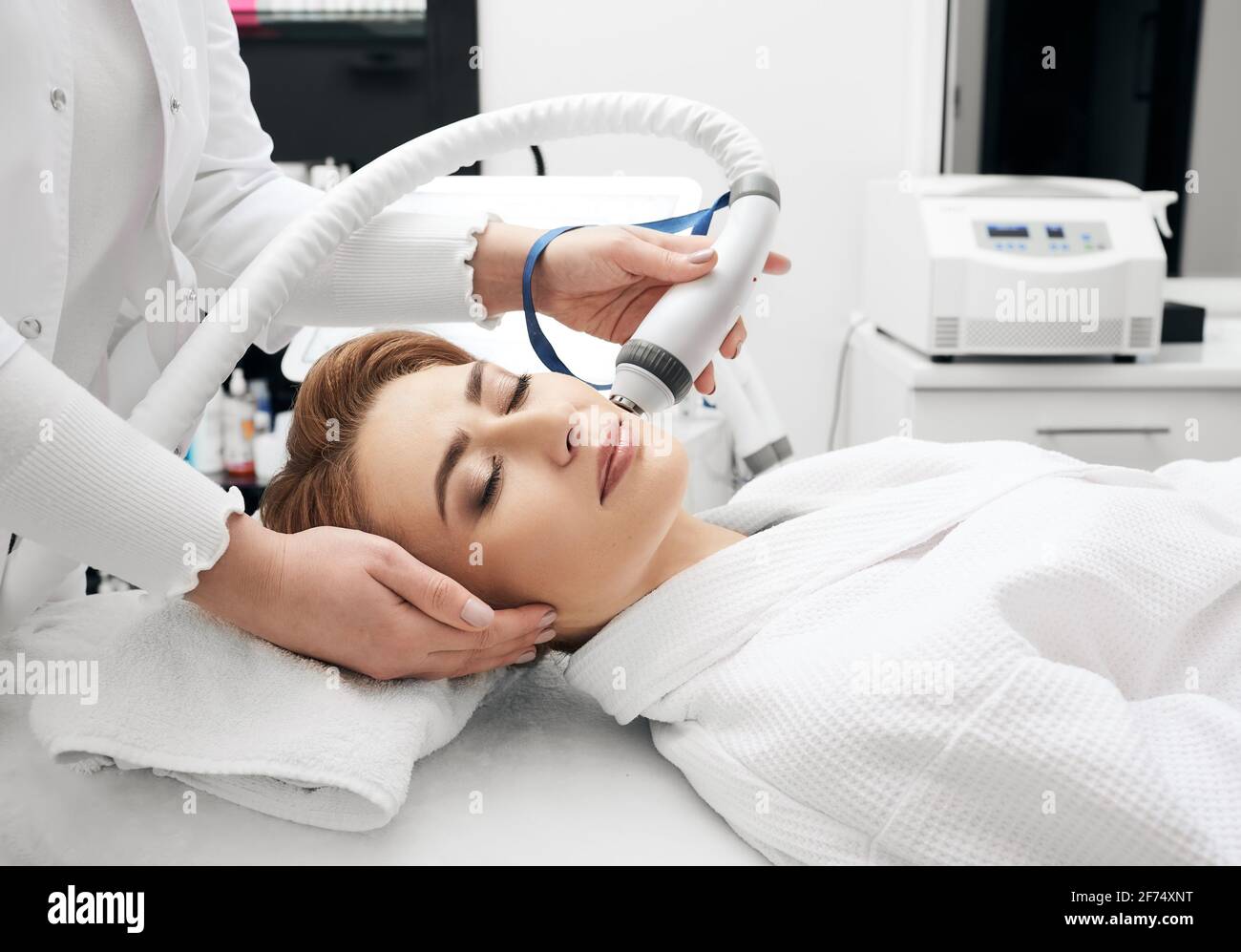 La donna ama la procedura di sollevamento rf per la pelle del viso stringendo con un cosmetologist ad un salone di bellezza Foto Stock