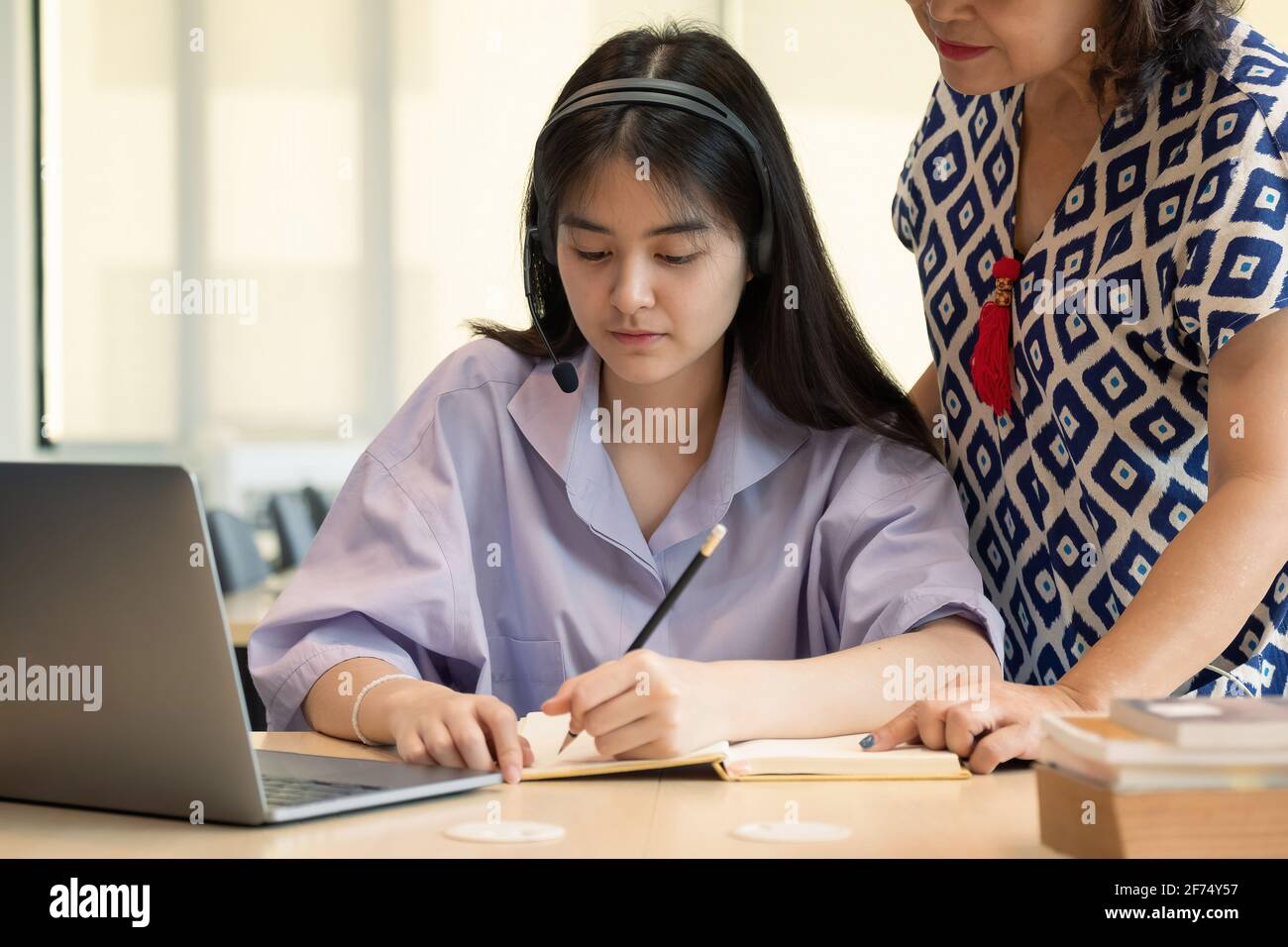 Madre asiatica con il notebook che insegna figlia per imparare o studiare in linea a casa, Homeschooling concetto in linea. Foto Stock