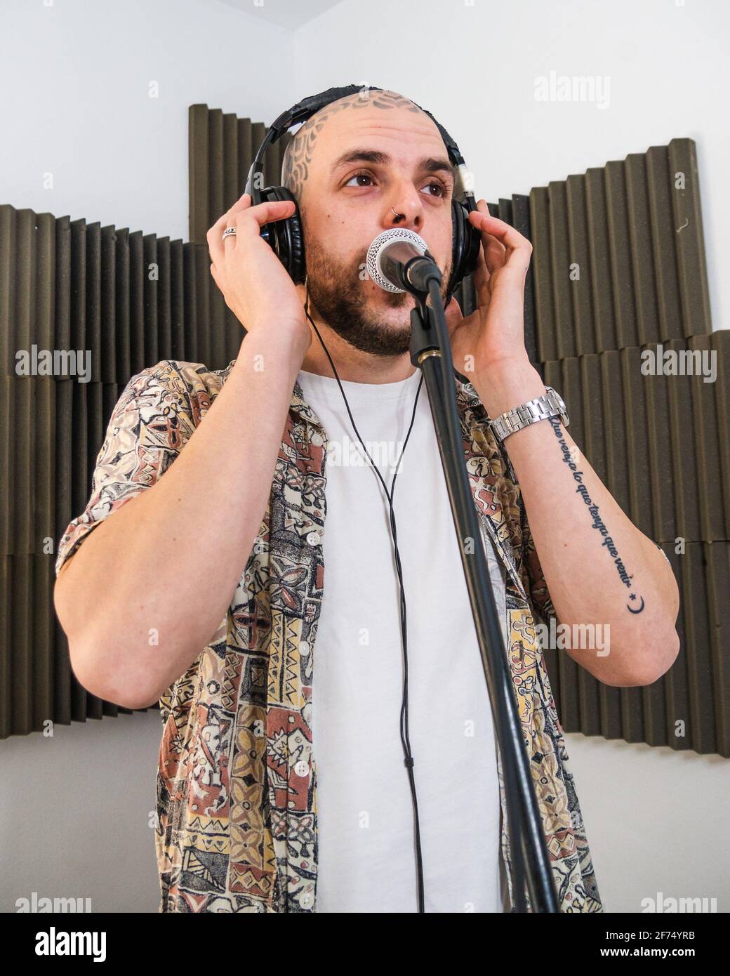 Uomo musicista messo a fuoco in abiti eleganti con cuffie in piedi e.  cantare nel microfono mentre si registra la canzone in studio Foto stock -  Alamy