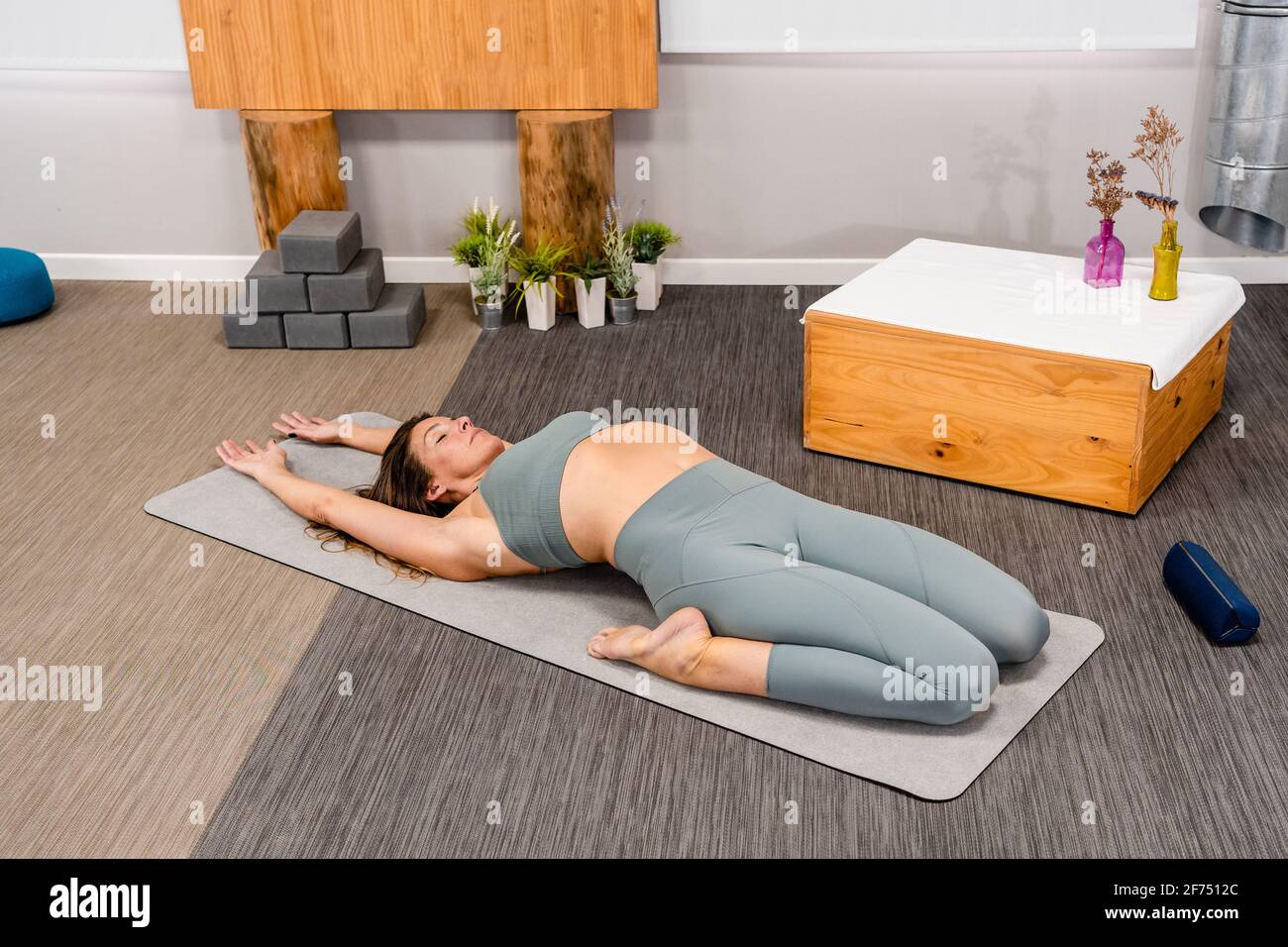 Dall'alto di flessibile giovane femmina in activewear ricreando in Utthita Supta Virasana posa con gli occhi chiusi mentre si pratica lo yoga a casa Foto Stock