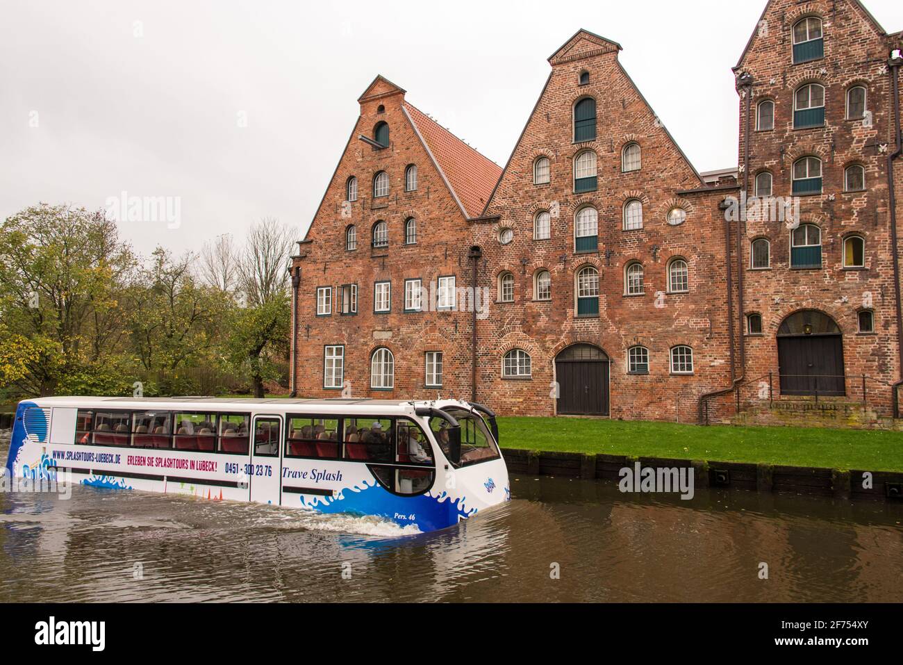 Un autobus turistico anfibio passa accanto ai magazzini storici di Lübeck, che in precedenza erano utilizzati per immagazzinare il sale. Foto Stock