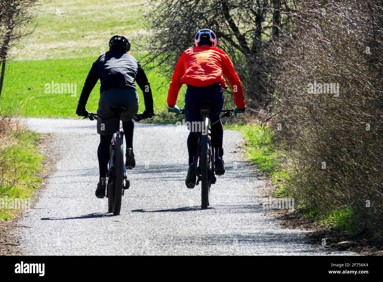 Due uomini in bicicletta in un paesaggio di campagna primaverile Foto Stock