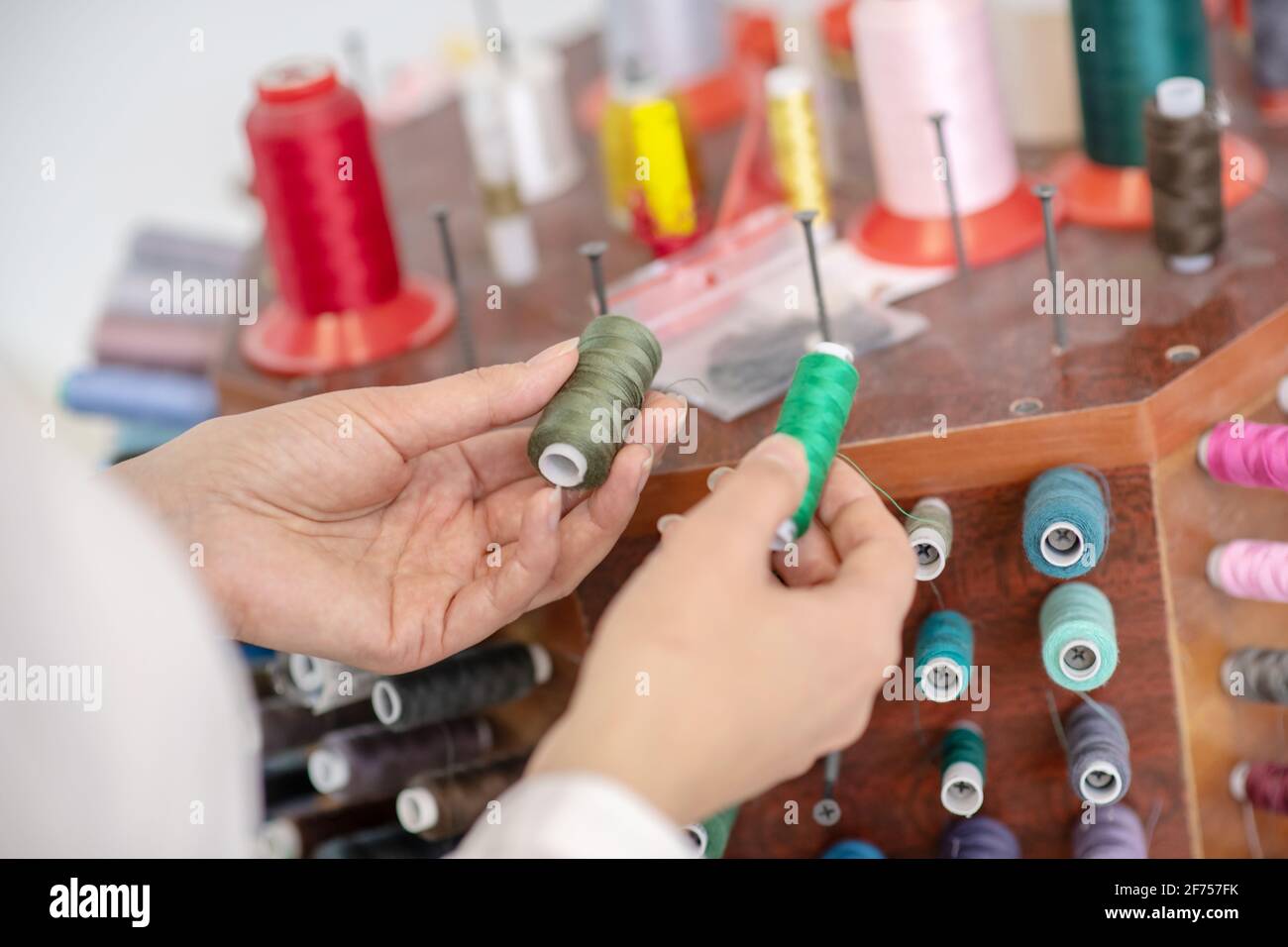 Le mani femminili scelgono la tonalità del filo verde Foto Stock