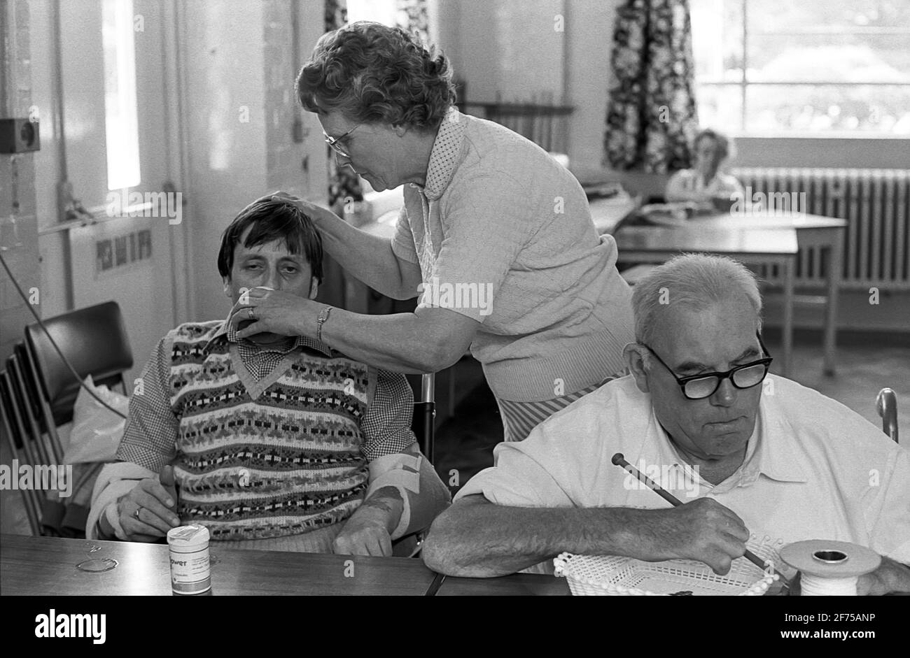 Strode Park un centro diurno per disabili fisici e mentali. Il caregiviere aiuta l'uomo a bere Foto Stock