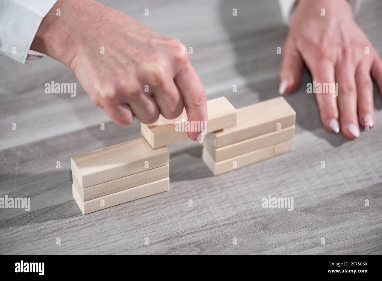 Mano femmina costruzione di un ponte con blocchi di legno; concetto di associazione Foto Stock