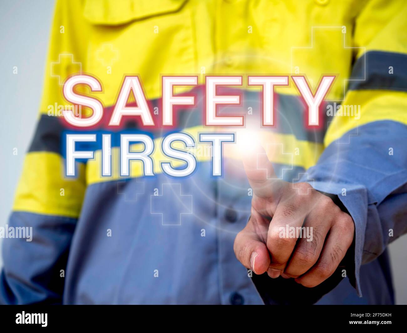 Concetto di sicurezza sul lavoro. Parola 'sicurezza prima' e simbolo di aiuto sul dito di puntamento di tecnici che indossano giacca gialla ad alta visibilità. Foto Stock