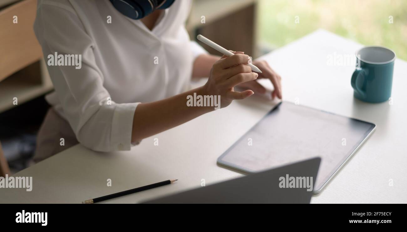 Primo piano uomo d'affari con la penna stilo, lavoro su tablet digitale sul posto di lavoro. Foto Stock