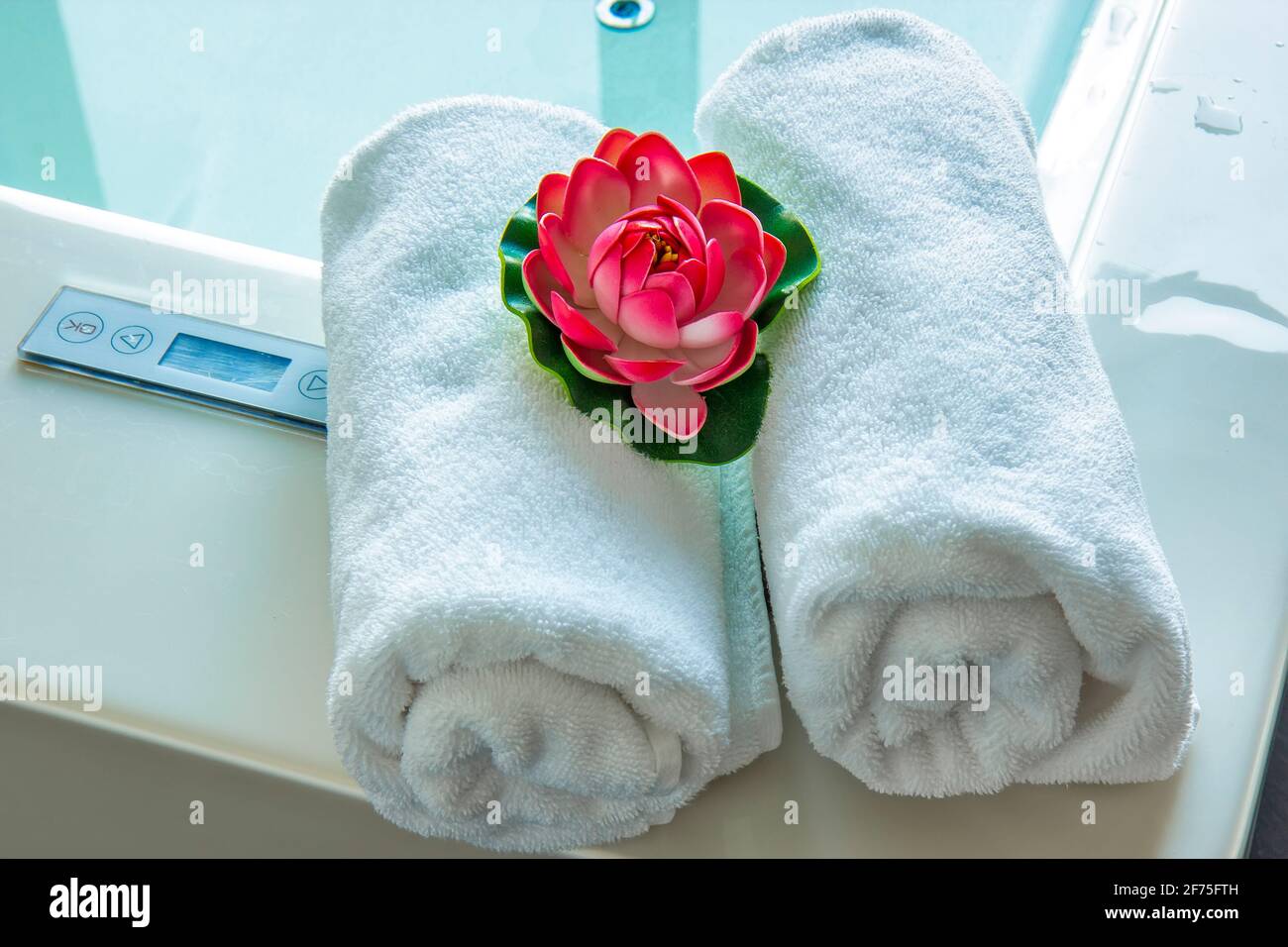 Asciugamani e giglio d'acqua nella vasca idromassaggio Foto Stock