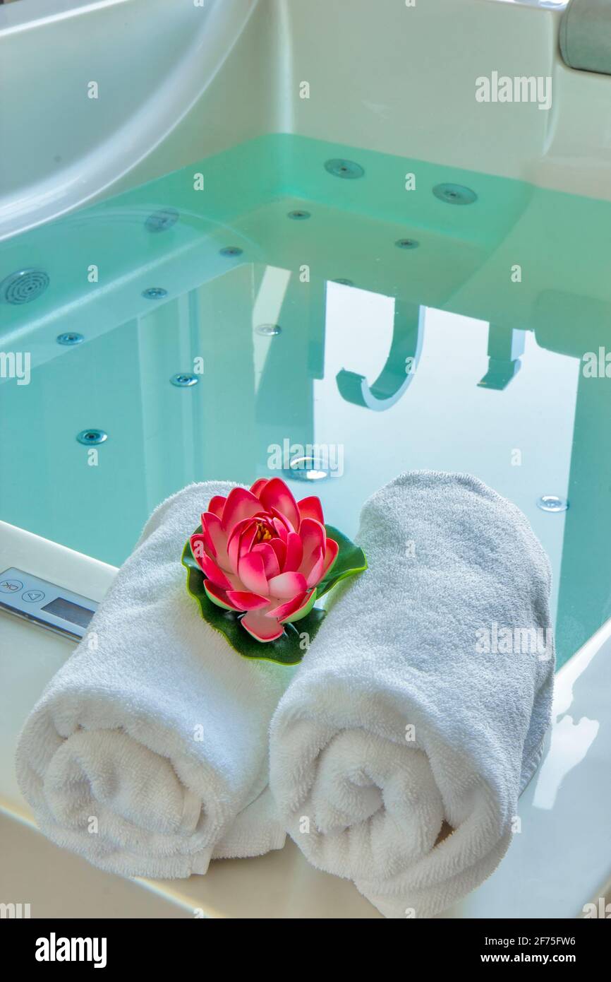 Asciugamani e giglio d'acqua nella vasca idromassaggio Foto Stock