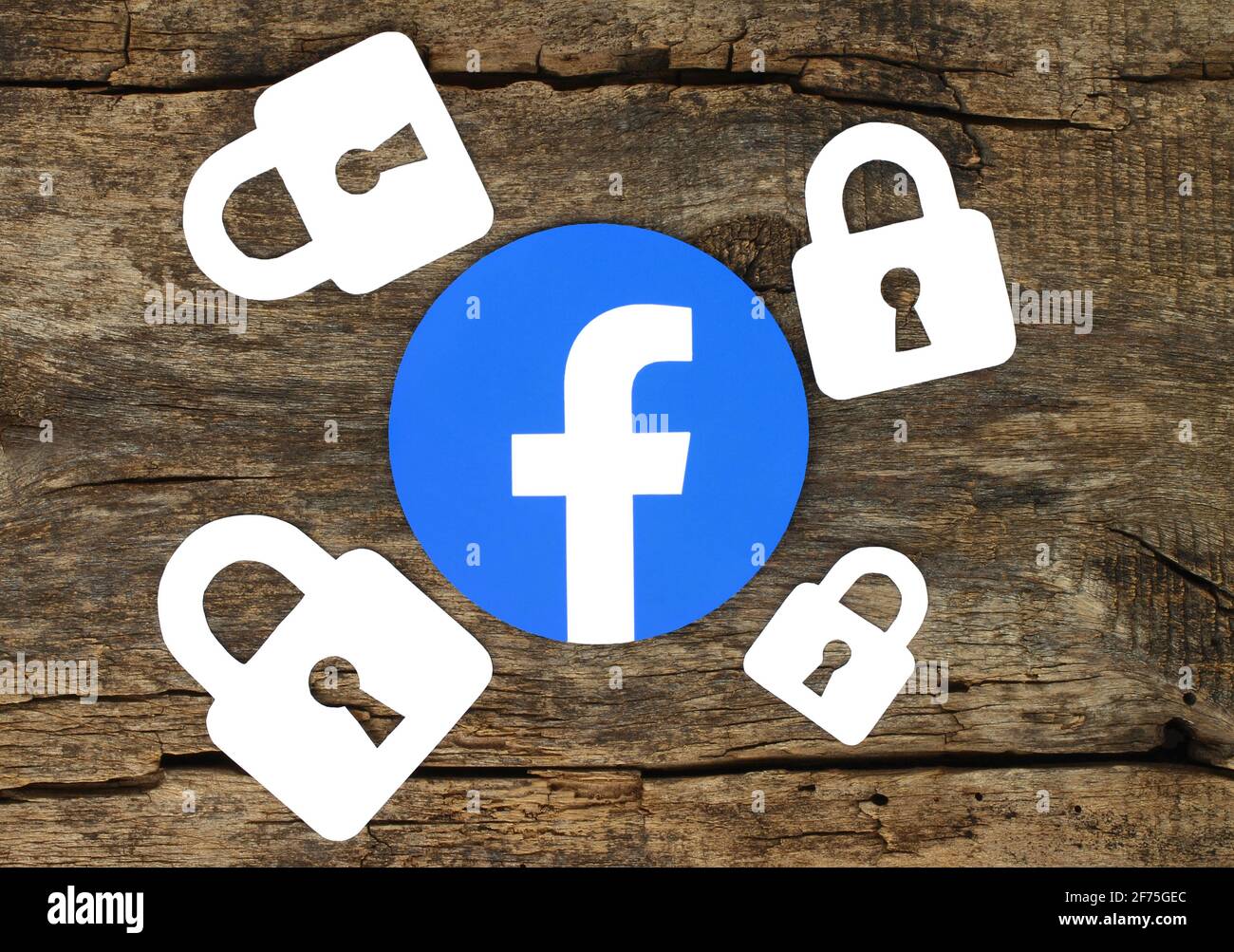 Kiev, Ucraina - 19 febbraio 2021: Icona di Facebook con serrature stampate su carta e poste su vecchio sfondo di legno. Problemi di sicurezza e privacy su Facebook Foto Stock