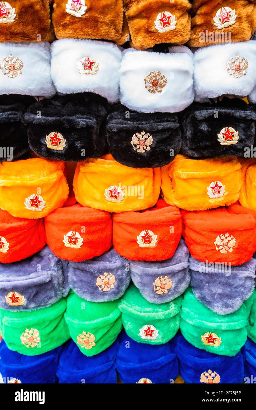 Mosca, Russia - 4 aprile 2021: File di cappelli invernali russi di diversi colori con emblemi dell'esercito al mercato di strada in Old Arbat Street, iconico popolare souvenir russo. Foto di alta qualità Foto Stock
