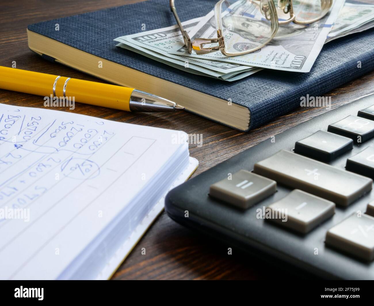 Calcoli finanziari nel blocco note, denaro e calcolatrice. Foto Stock
