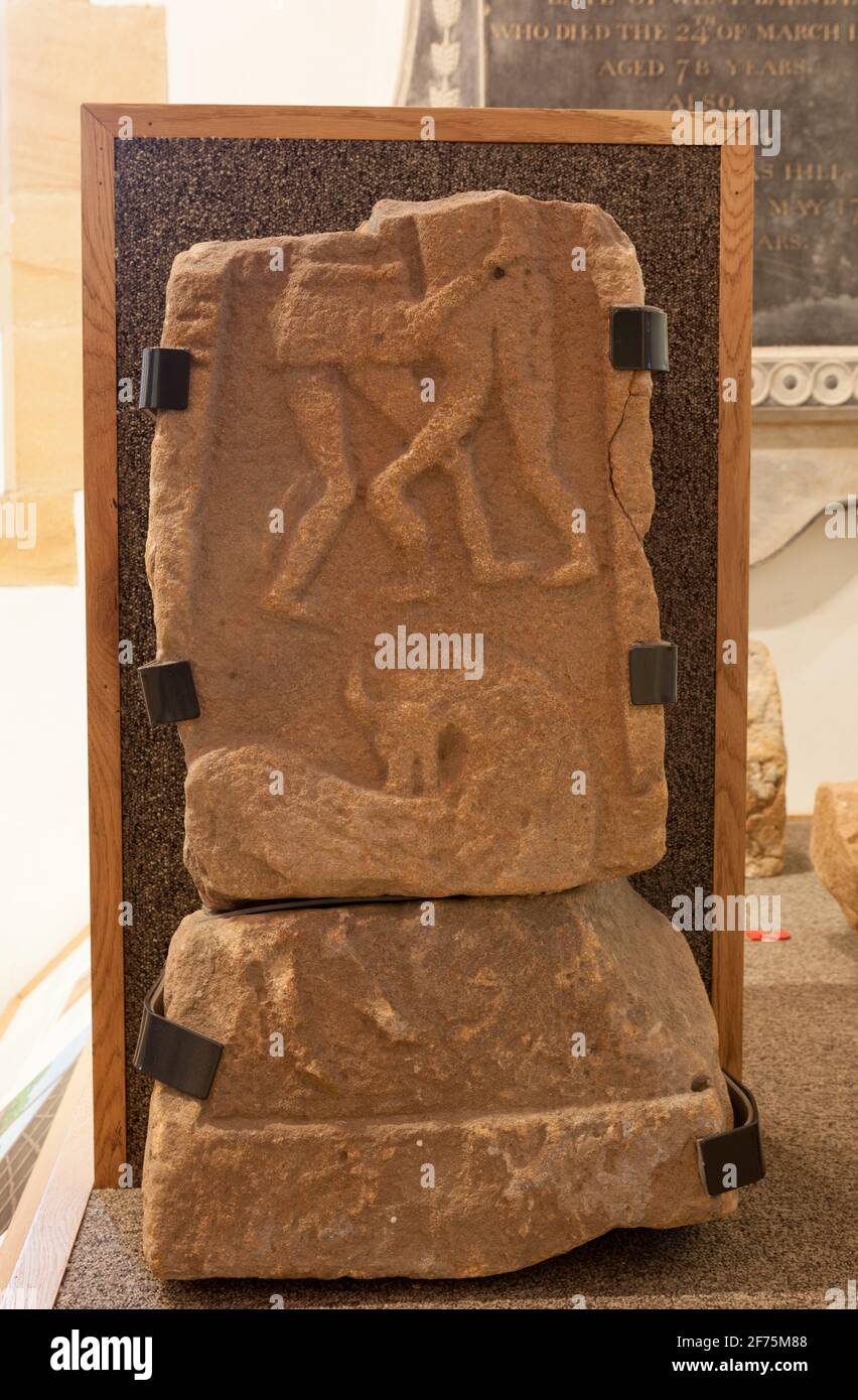 Un antico frammento di albero trasversale del X secolo esposto nella chiesa di St. Oswald Lythe sulla costa dello Yorkshire con due figure scolpite che lottano Foto Stock