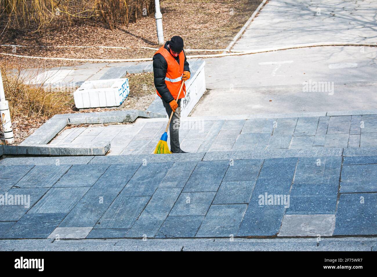 Dnepropetrovsk, Ucraina - 03.16.2021: I servizi municipali stanno pulendo la città dopo l'inverno. Un lavoratore spazza una scala di granito in un parco da ultimo y Foto Stock