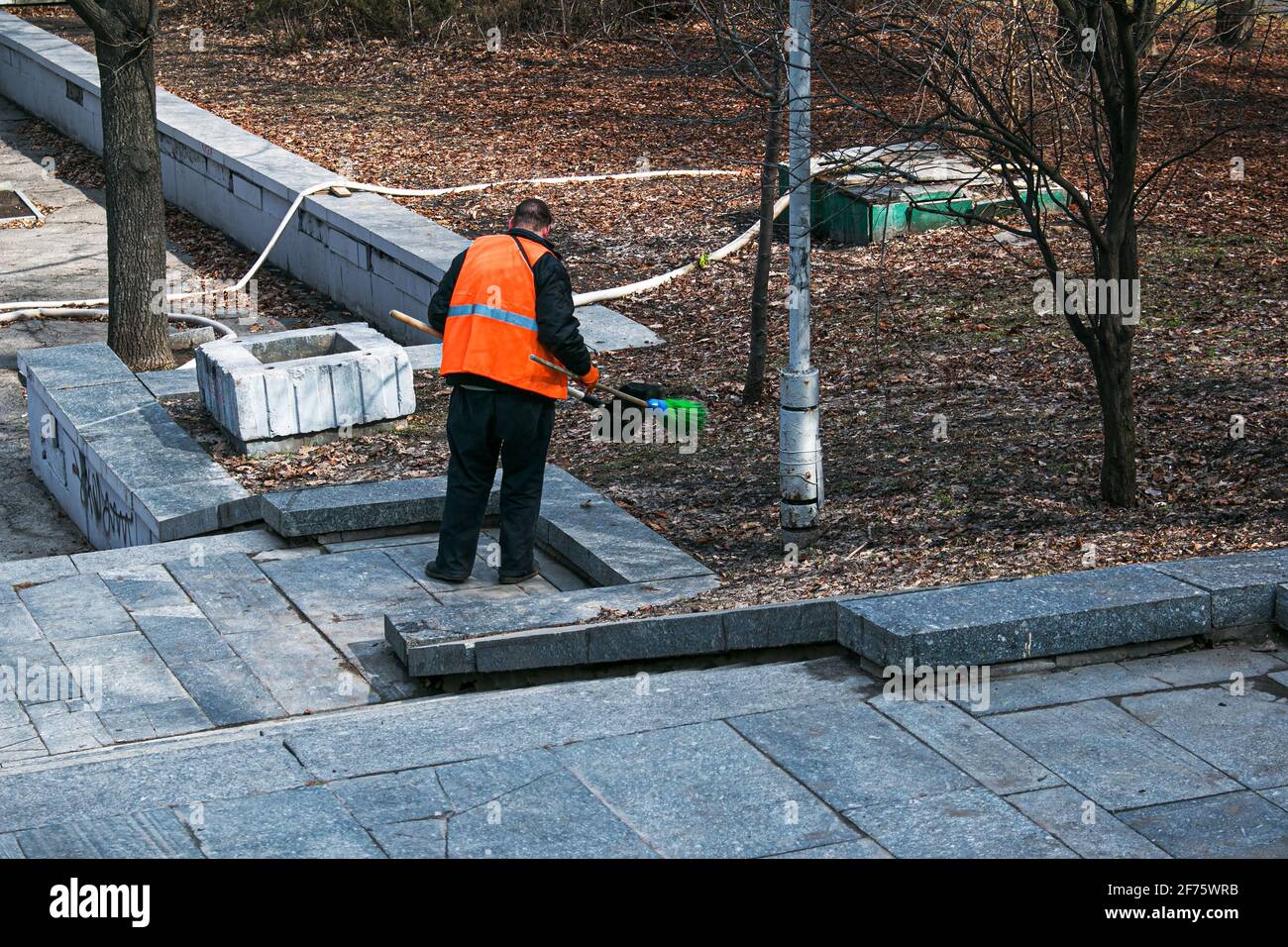 Dnepropetrovsk, Ucraina - 03.16.2021: I servizi municipali stanno pulendo la città dopo l'inverno. Un lavoratore spazza una scala di granito in un parco da ultimo y Foto Stock