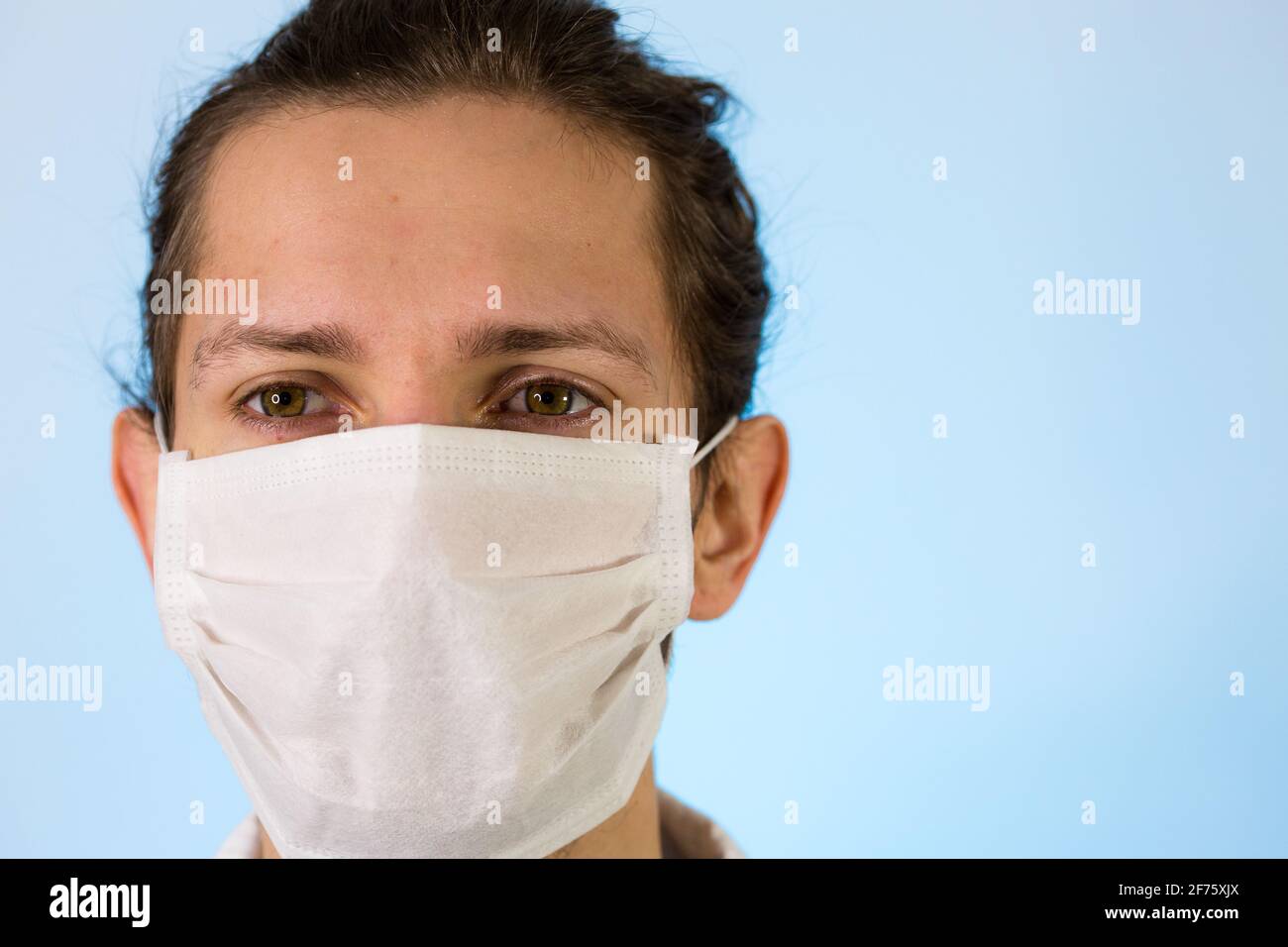 Un maschio adulto vestito con un camice da laboratorio bianco con una maschera protettiva sul viso. Pronto a lavorare in un ambiente pulito o in laboratorio Foto Stock