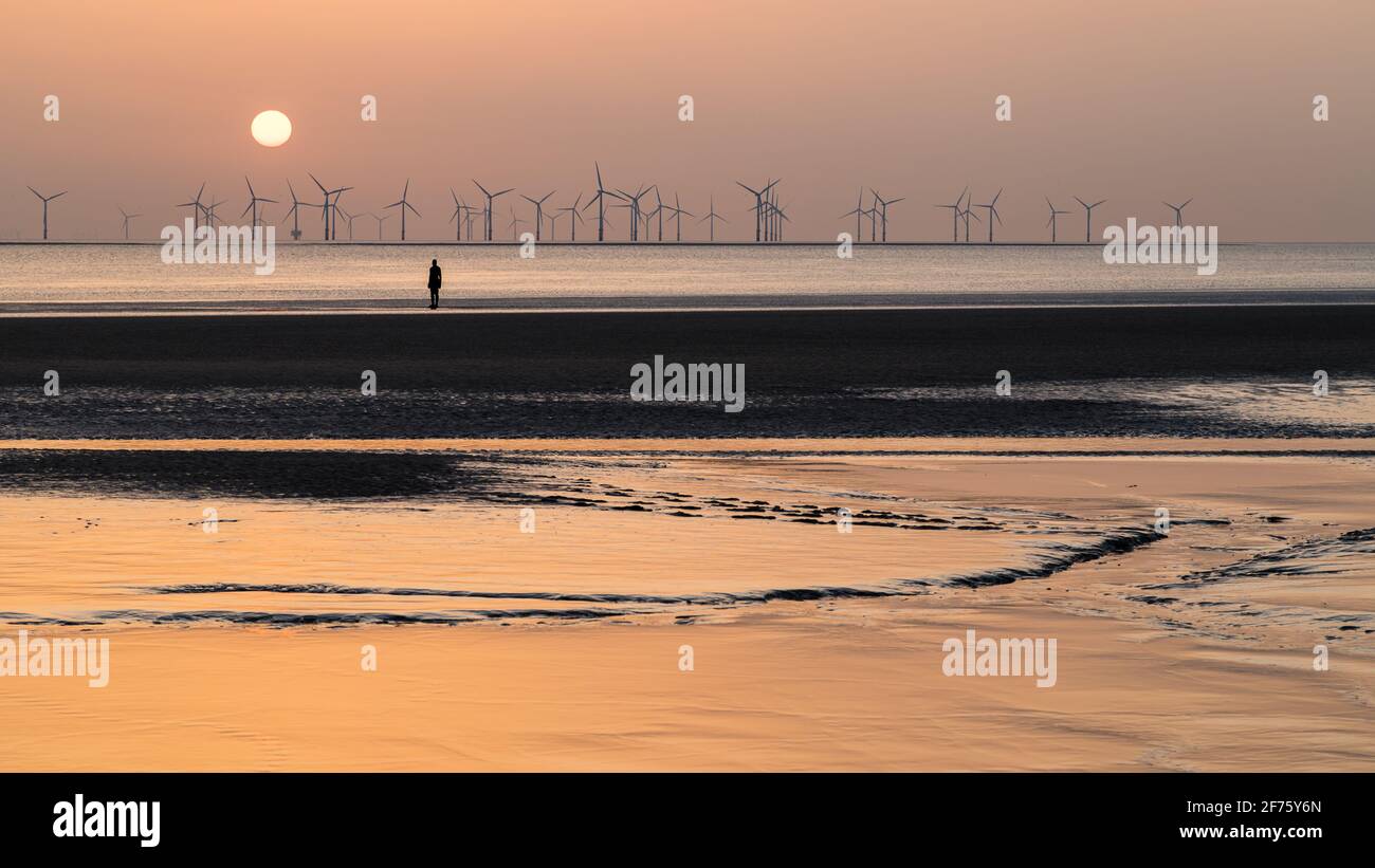 La colorata luce del sole si riflette fuori dal limo sulla spiaggia di Crosby al tramonto nell'aprile 2021. È una delle cento statue di uomini di ferro che compongono Antony Foto Stock