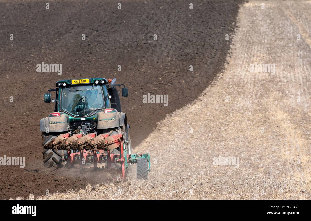 Aratura dell'agricoltore nelle stoppie dopo la raccolta del prodotto, utilizzando un trattore Valtra e un aratro a 5 solchi. North Yorkshire, Regno Unito. Foto Stock