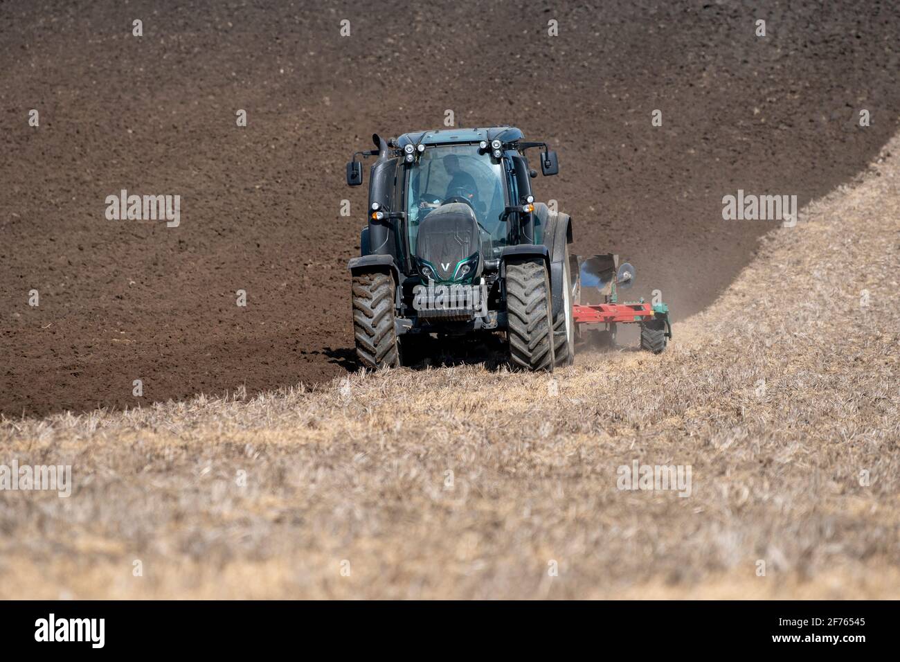 Aratura dell'agricoltore nelle stoppie dopo la raccolta del prodotto, utilizzando un trattore Valtra e un aratro a 5 solchi. North Yorkshire, Regno Unito. Foto Stock