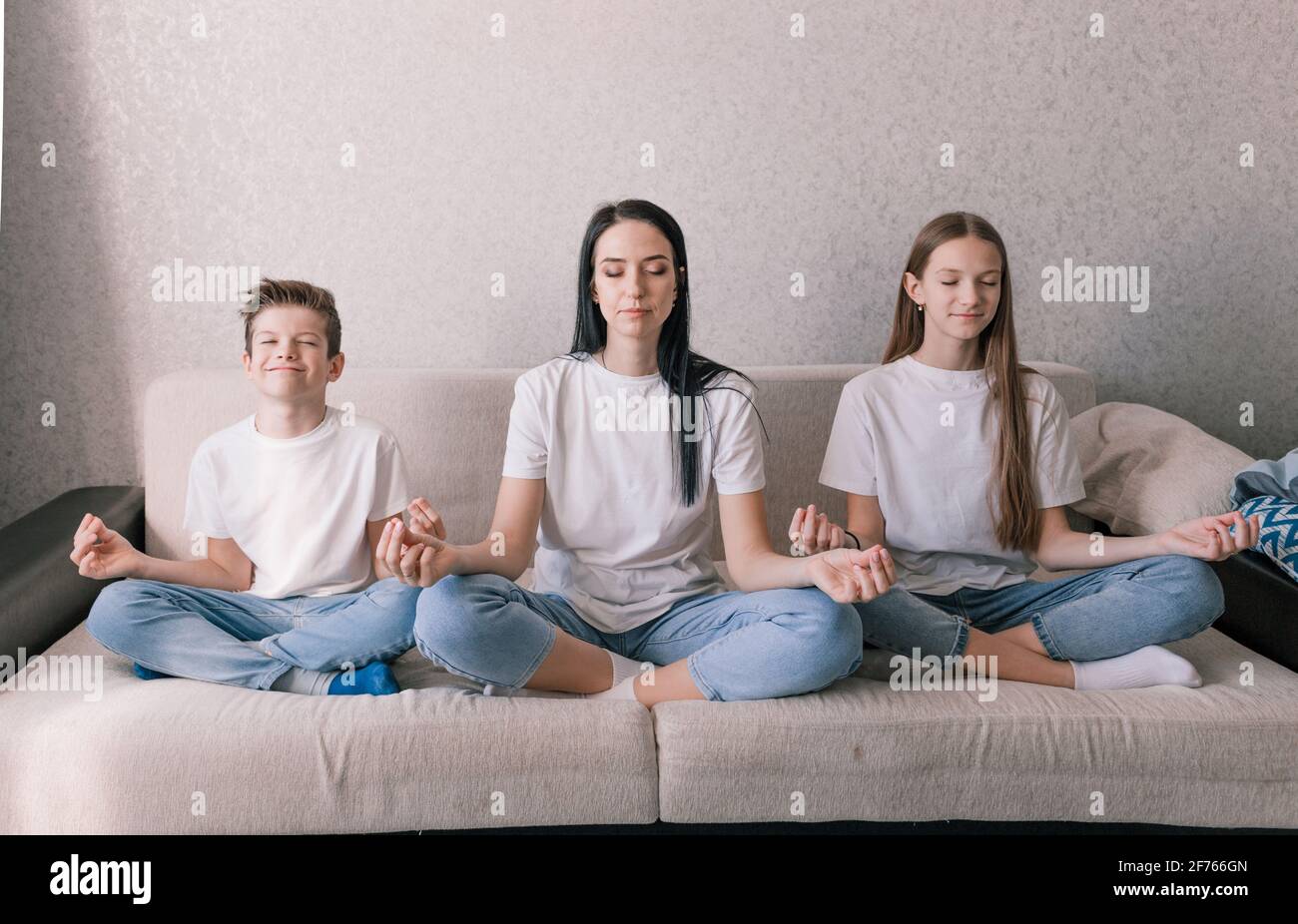 madre figlia e figlio sono seduti sul divano nella posizione di loto  impegnata nella meditazione Foto stock - Alamy