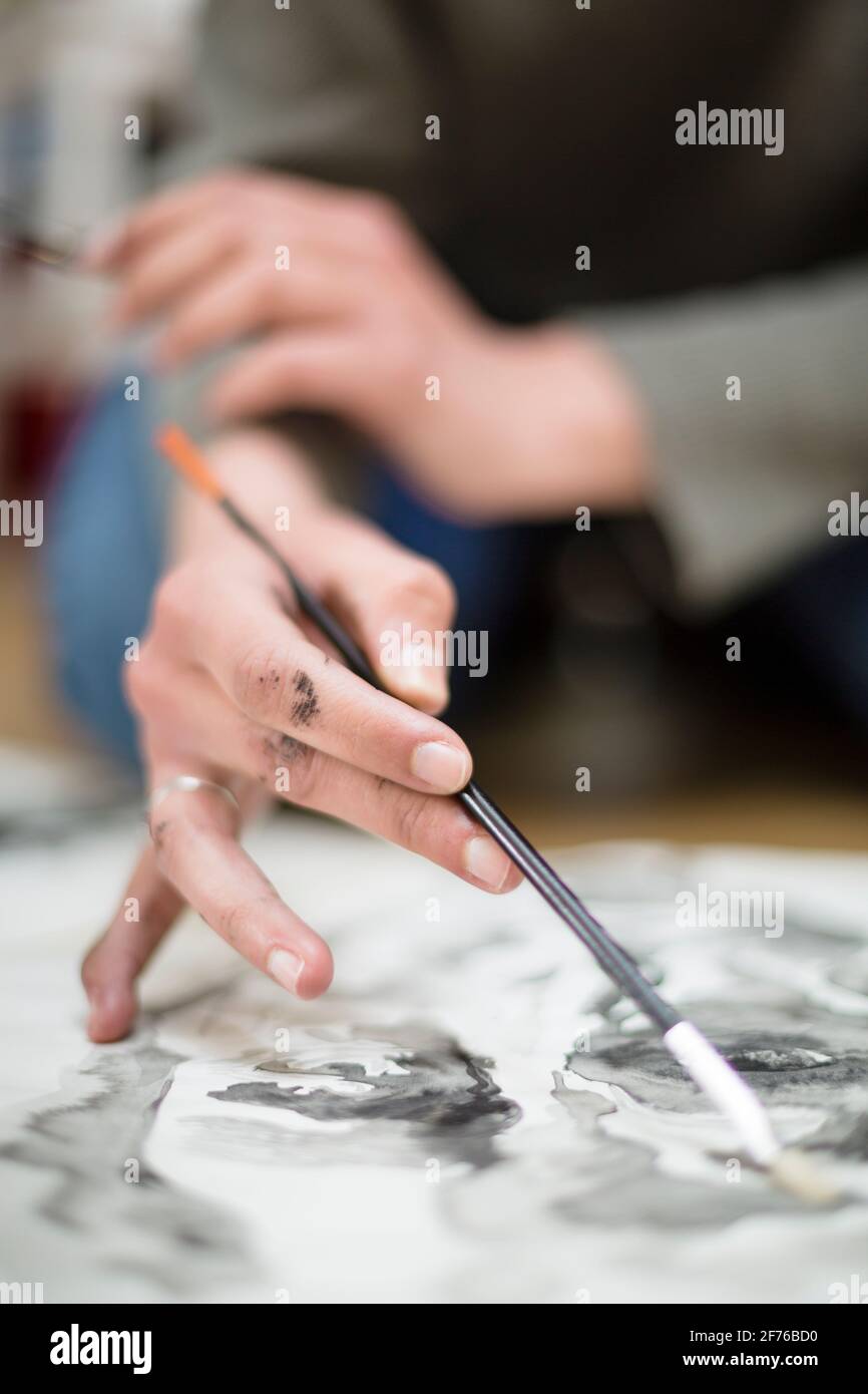 Primo piano del dettaglio delle mani di un artista irriconoscibile mentre sta dipingendo con acquerelli su una tela. Concetto di arte. Messa a fuoco selettiva. Spazio Foto Stock