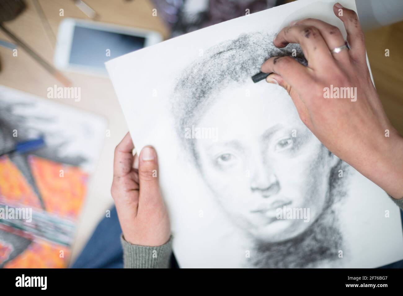 Vista dall'alto di un primo piano delle mani di una persona che disegna un ritratto in carbone su una tela. Concetto di classi di pittura. Messa a fuoco selettiva. Spazio per te Foto Stock