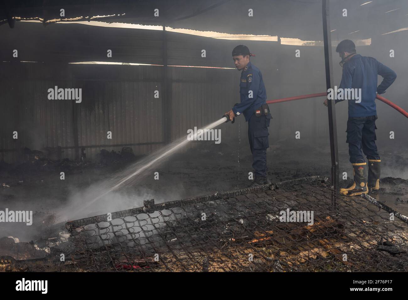 I vigili del fuoco vedevano spegnere alcuni degli articoli ancora in fiamme nel warehouse.Today un incendio scoppiò e ingolfò un magazzino a Kendari. Secondo i testimoni oculari, l'incendio è stato innescato da un corto circuito di elettricità che ha catturato fiamme dopo aver colpito una bombola di gas e una motocicletta all'interno del magazzino. Foto Stock