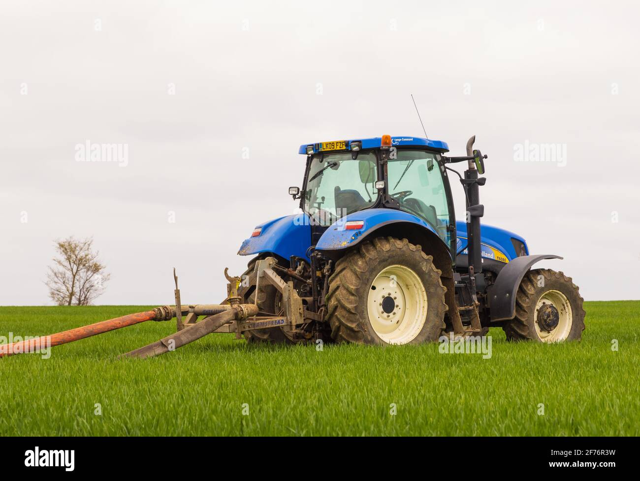 Trattore utilizzato per trainare il tubo flessibile ombelicale collegato a uno spanditore di liquame su un altro trattore. REGNO UNITO. Foto Stock