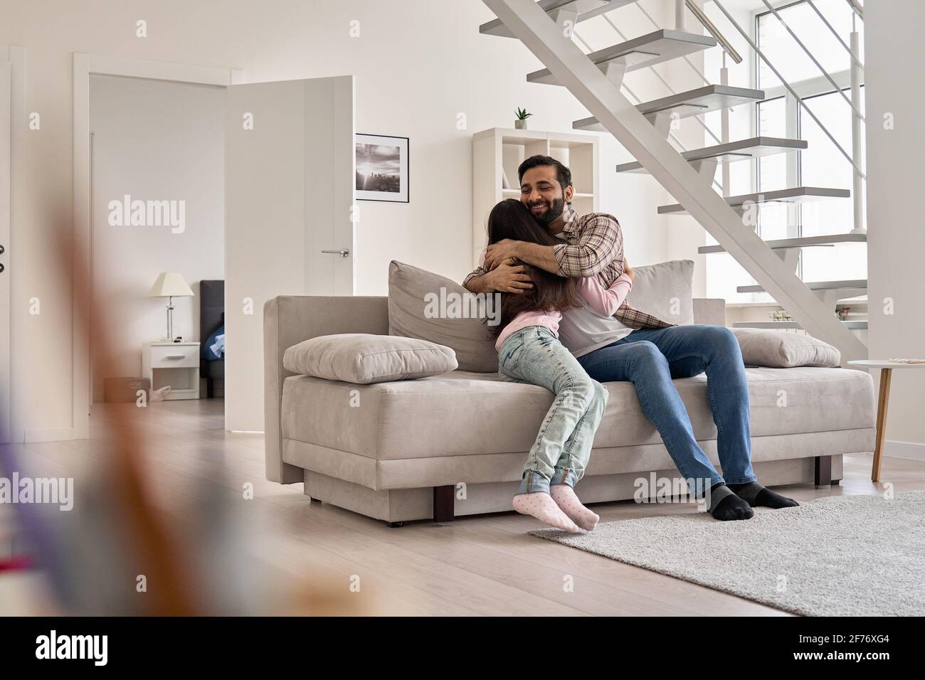 Felice famiglia indiana figlia adolescente hugging padre bonding sul divano a casa. Foto Stock