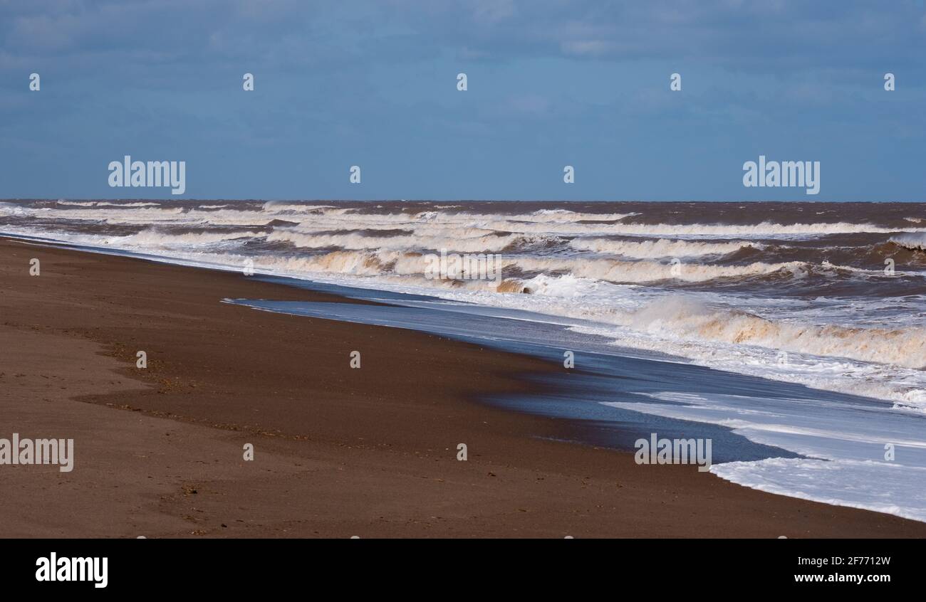 Potenti onde del Mare del Nord che colpiscono le spiagge di La costa del Lincolnshire che mostra la potenza grezza del mare e la vita ricercata dalla gente della città Foto Stock