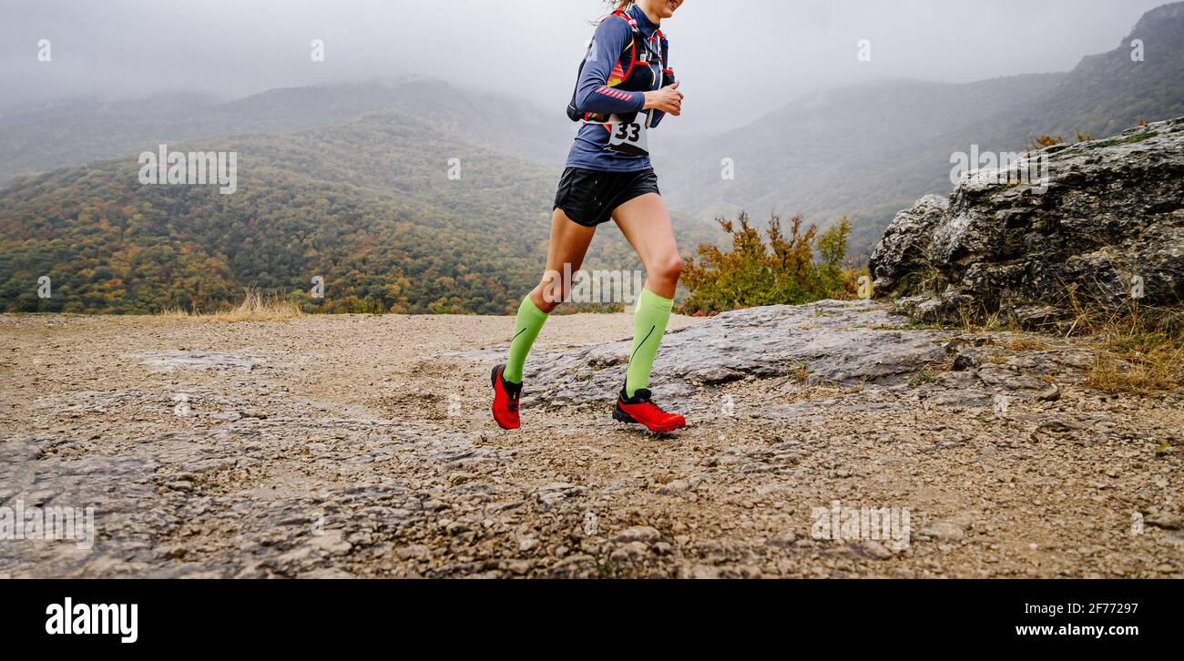 atleta giovane donna che corre pista di montagna in tempo nuvoloso Foto Stock