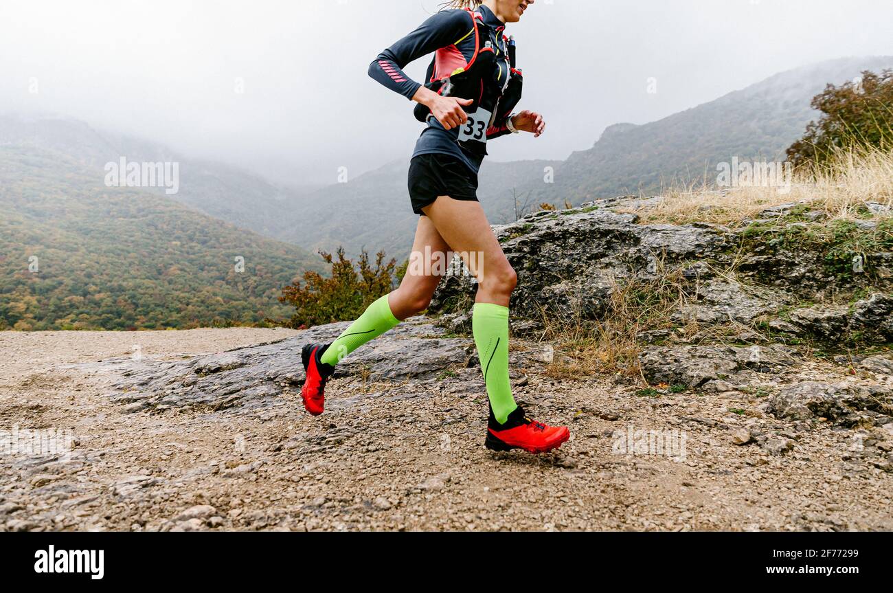 atleta donna che corre pista di montagna in calze di compressione Foto Stock