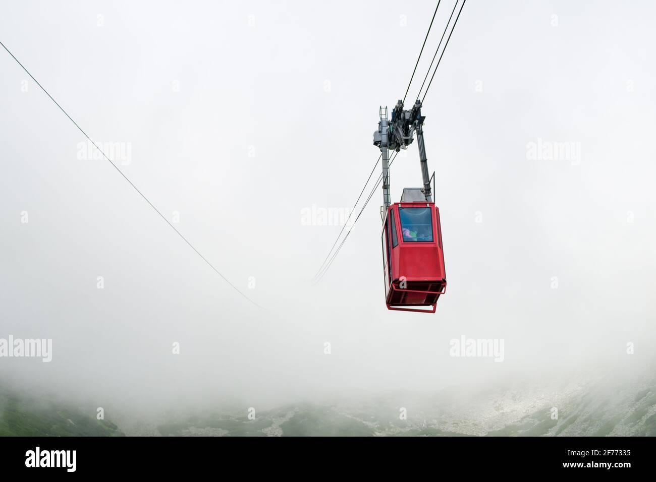 Funicolare rossa o funivia a sospensione rossa per Lomnicky picco in nebbia o nuvole, High Tatry, Slovacchia Foto Stock