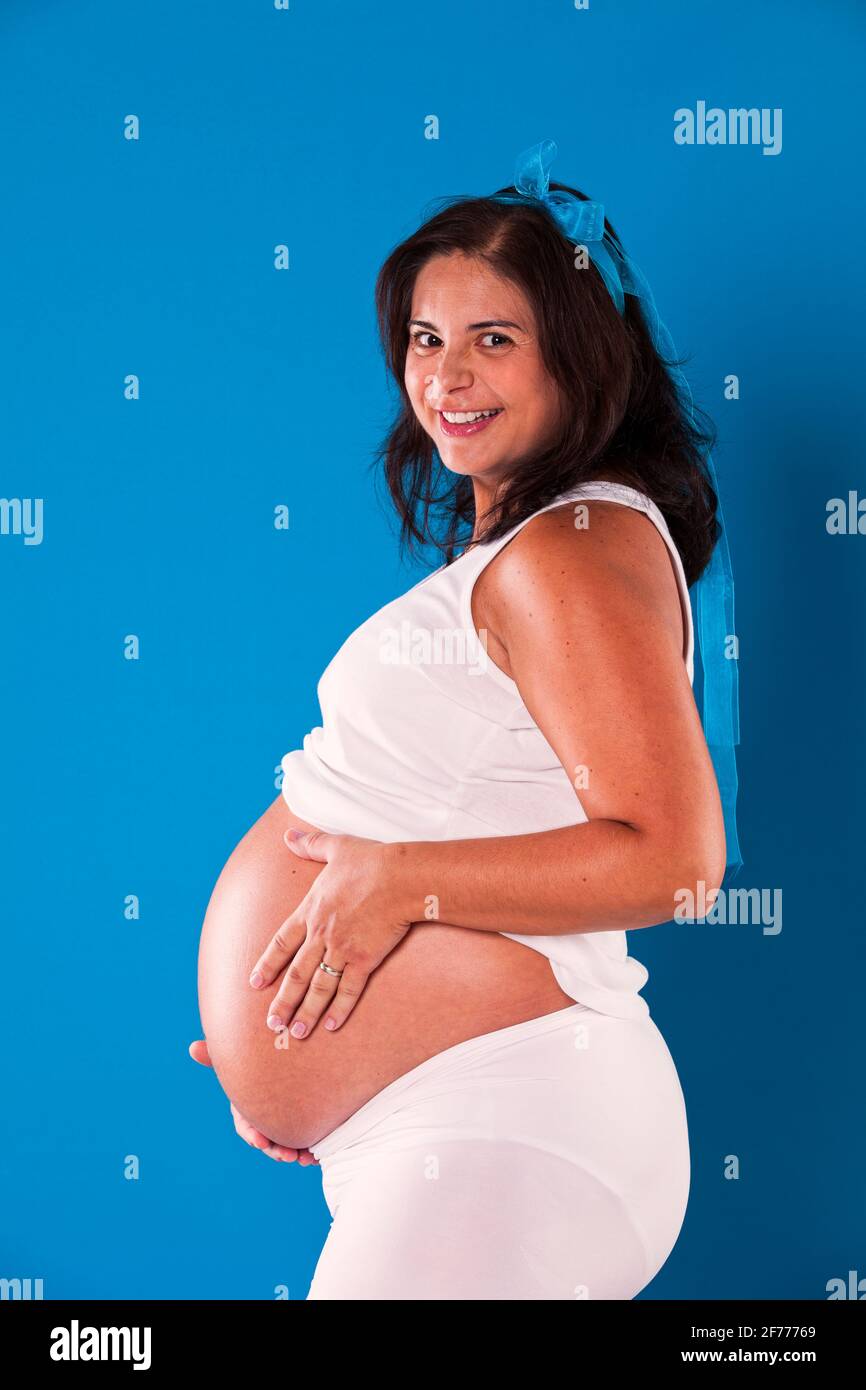 Donna in gravidanza felice con sfondo blu Foto Stock