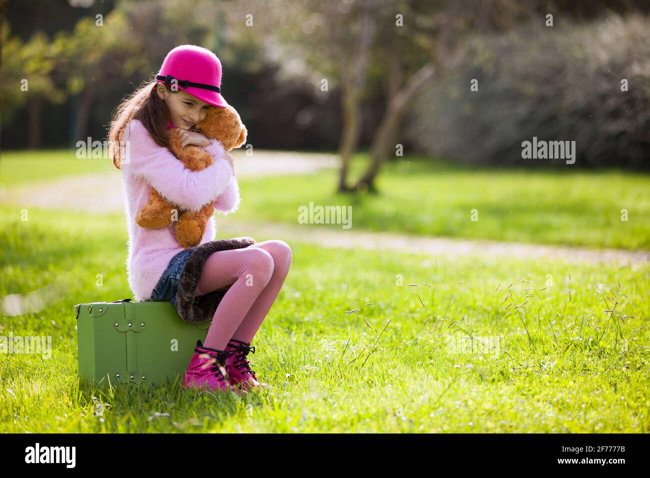 La bambina da sola si siede su una valigia Foto Stock