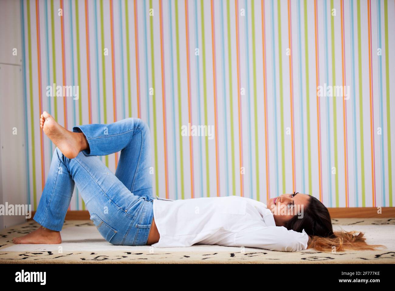 Donna sdraiata nel tappeto a casa Foto Stock