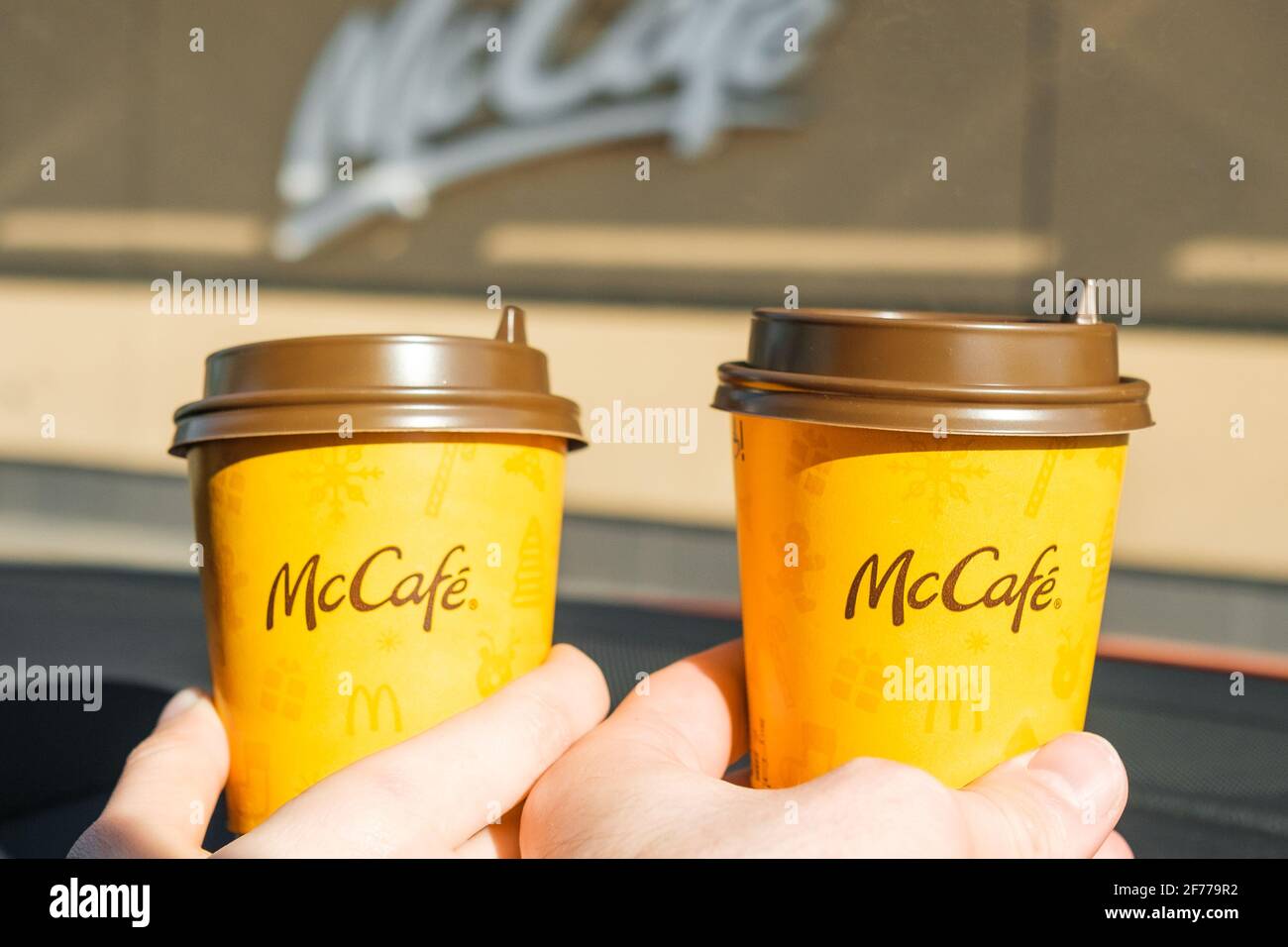Caffè da Mc Cafe in auto in mano donna e uomo, marzo 2021, Praga, Repubblica Ceca. Foto Stock