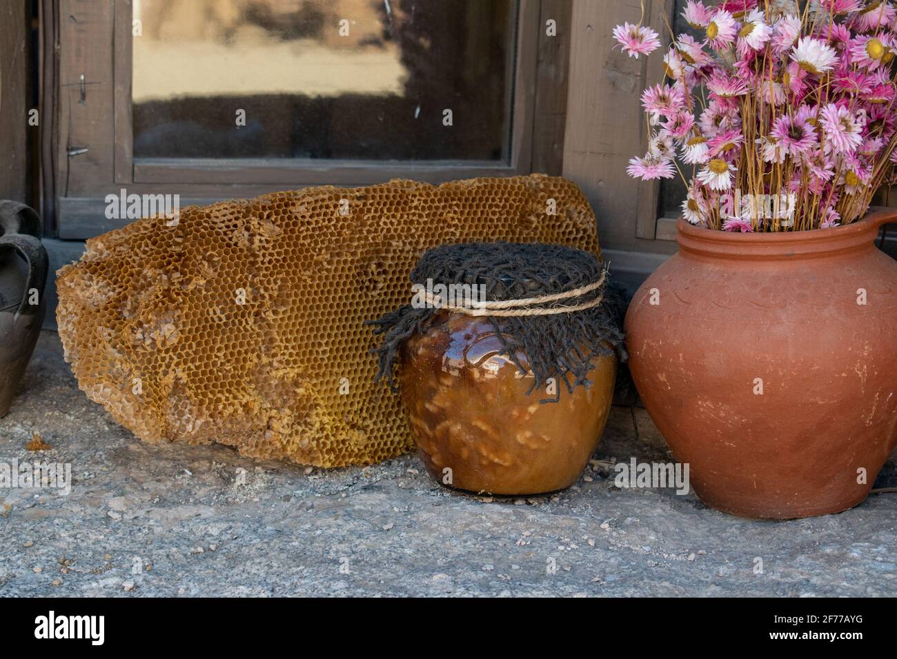 vaso di miele con fiori su tavolo di legno con pannello di ape dietro Foto Stock