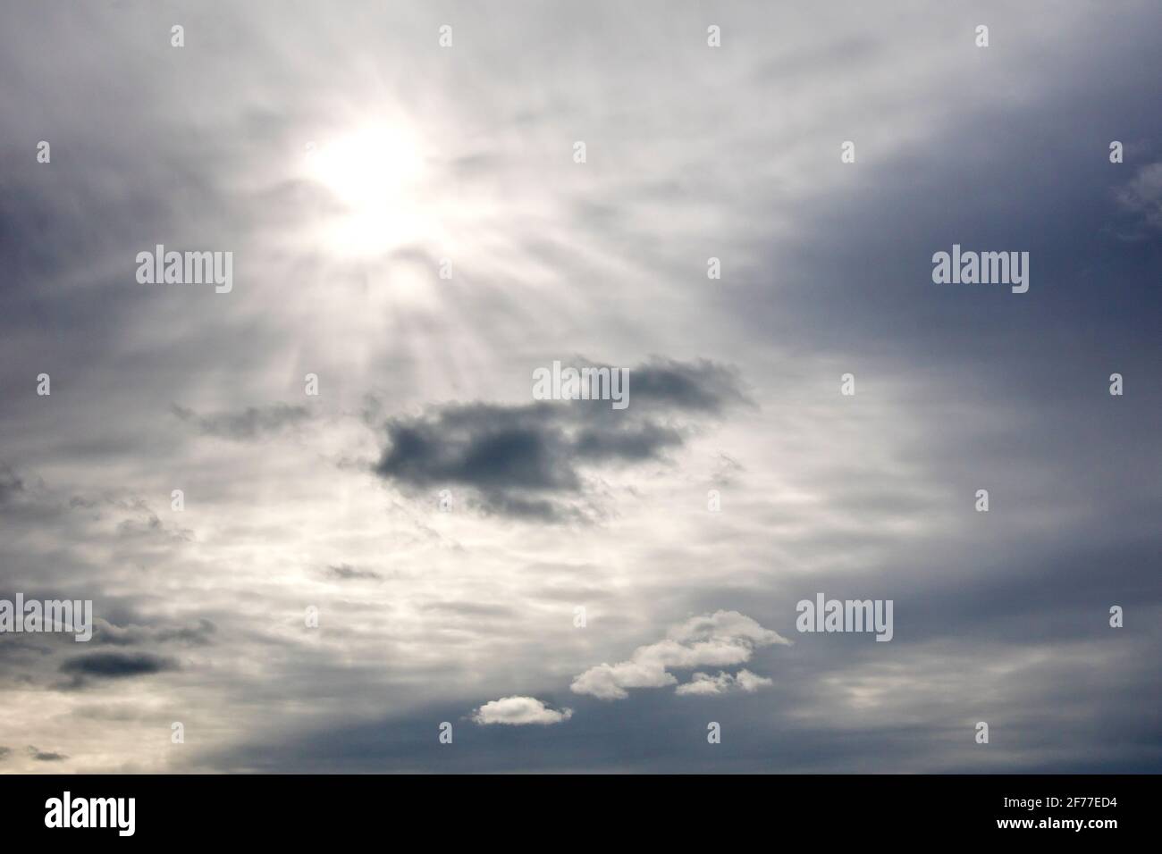 Un cielo sovrastato, la nuvola abbastanza sottile da consentire al sole di brillare debolmente attraverso e illuminare alcune nuvole di livello inferiore. Foto Stock