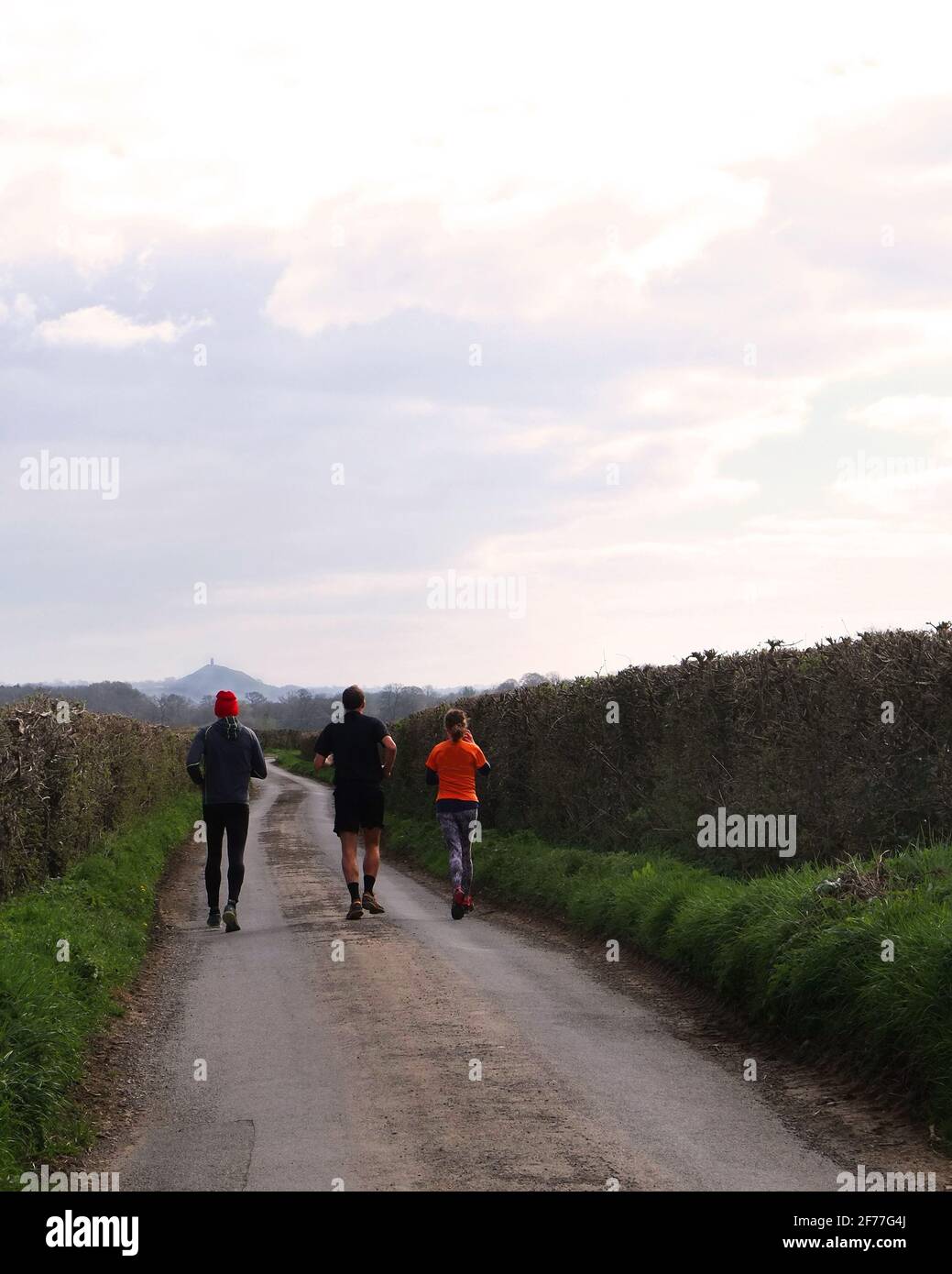 2021 aprile - tre corridori che si corrono verso il Tor a Glastonbury a Somerset, Regno Unito. Foto Stock