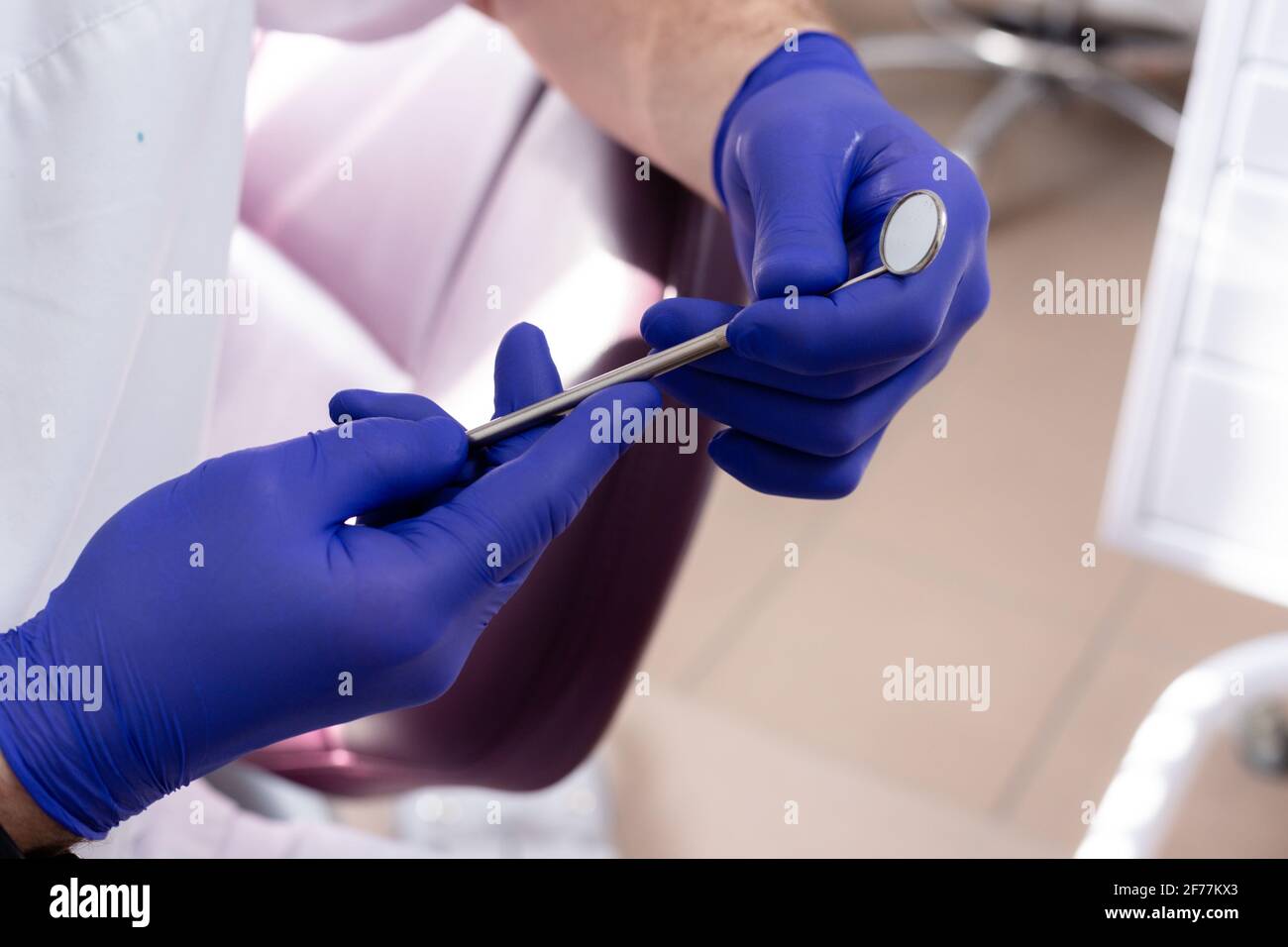 Specchio dentale in mani maschili con guanti medici blu Foto Stock