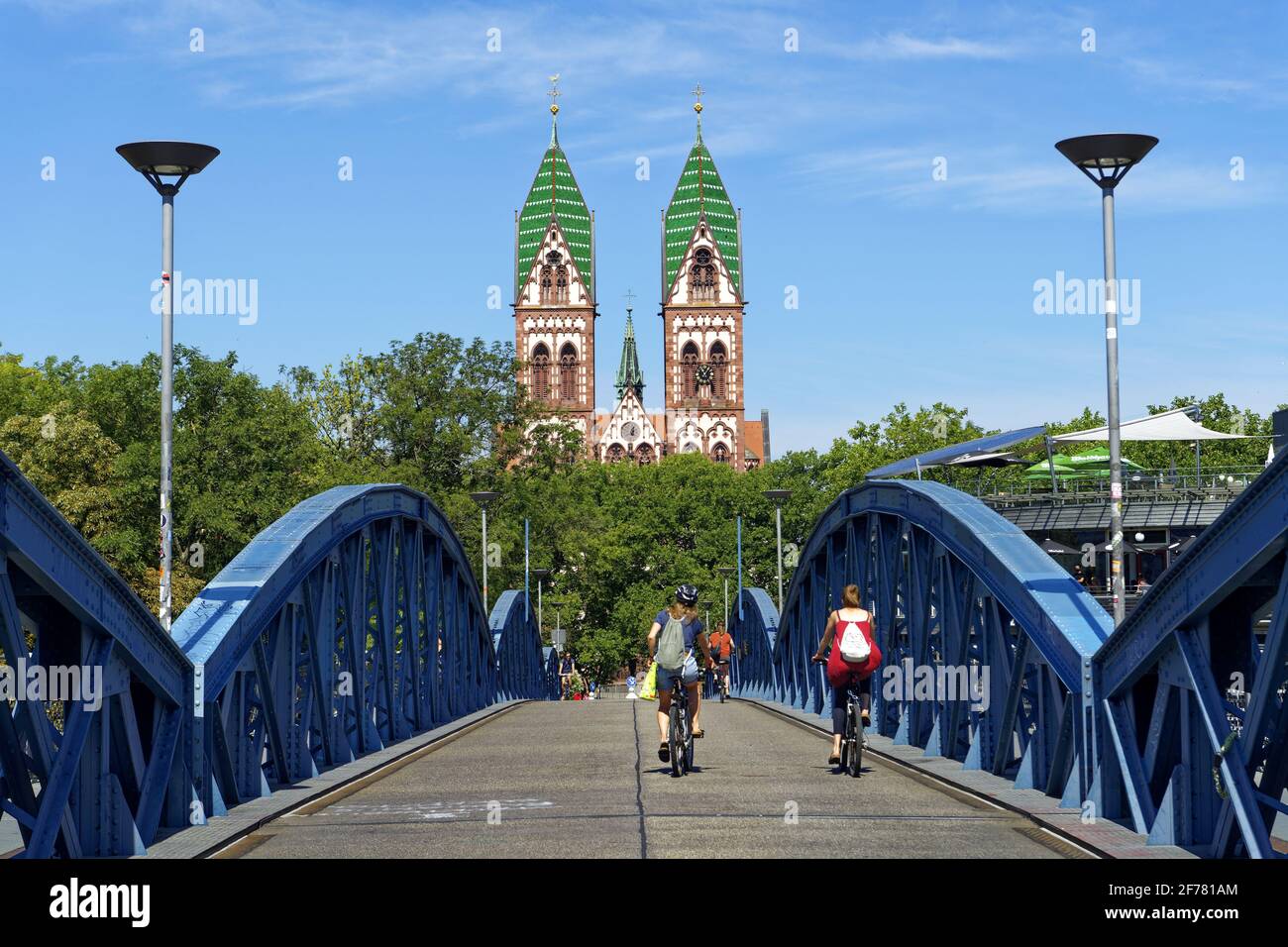 Germania, Baden Wurttemberg, Freiburg im Breisgau, ciclista sul ponte blu (ponte wilwili) e il Sacro cuore della Chiesa di Gesù (Herz Jesu kirche) Foto Stock