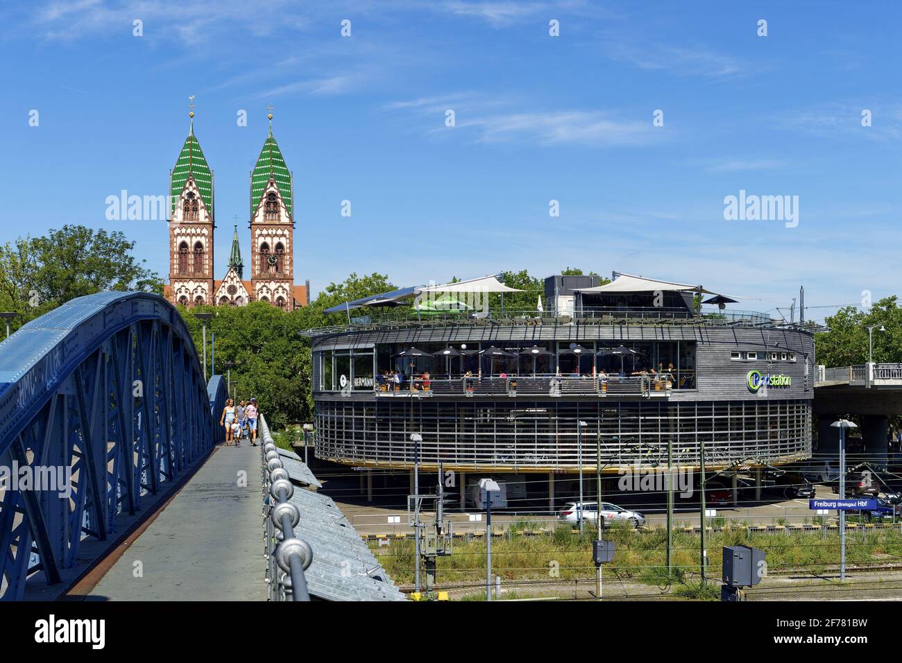 Germania, Baden Wurttemberg, Freiburg im Breisgau, il ponte blu (ponte wilwili), il Sacro cuore di Gesù Chiesa (Herz Jesu kirche) e la stazione di bicicletta chiamata Mobile presso la stazione centrale Foto Stock